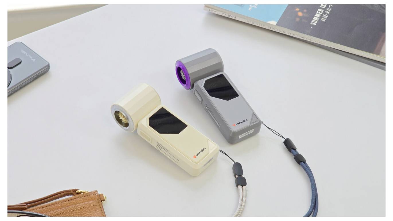 Zwei tragbare elektronische Geräte liegen auf einem Tisch, eines beige und eines grau, jeweils mit einem kreisförmigen linsenähnlichen Ende und angebrachten Kabeln.
