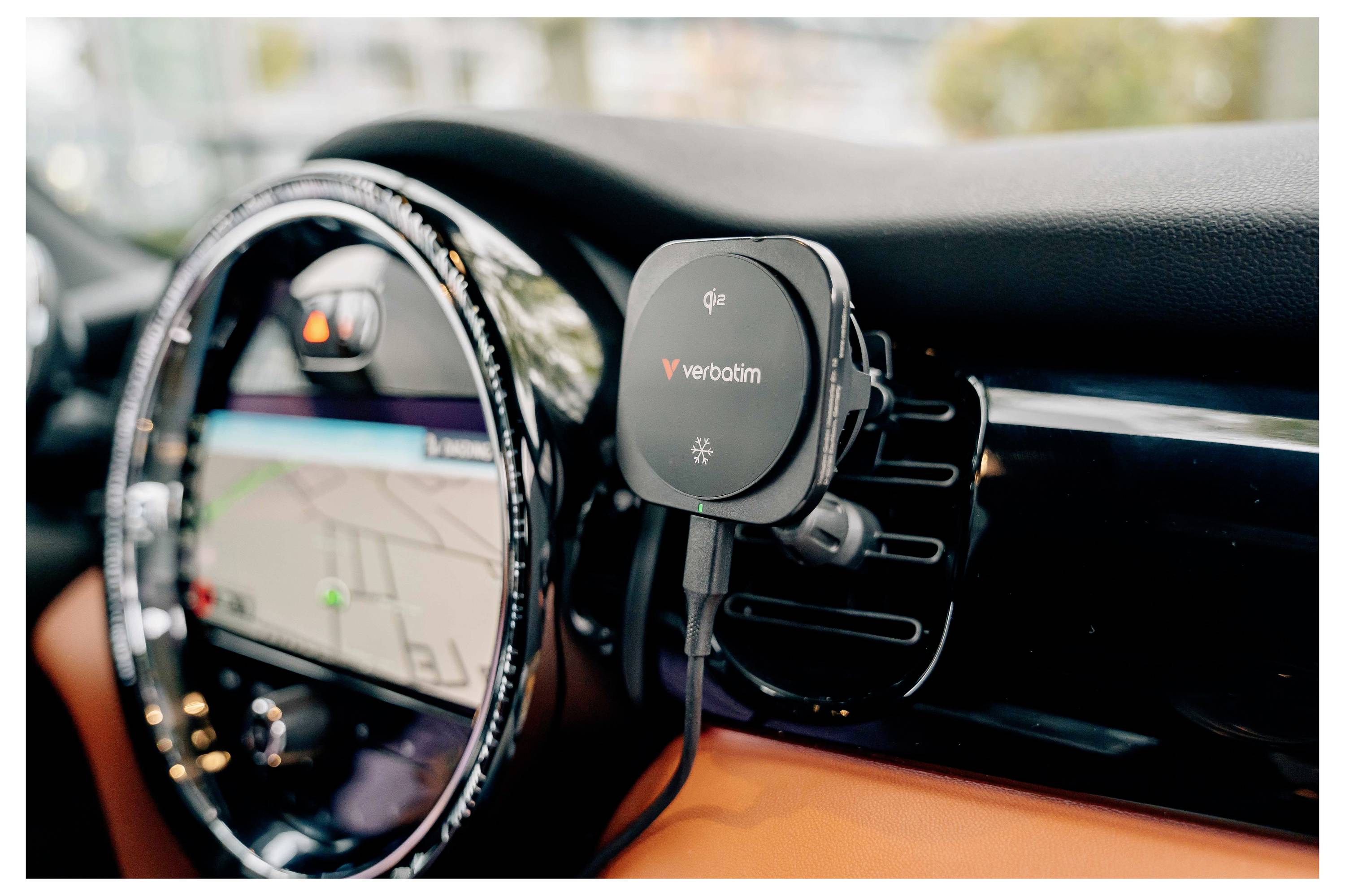 Ein Auto-Armaturenbrett mit einem montierten kabellosen Verbatim-Handyladegerät neben dem mittleren Lüftungsschlitz und dem Navigationsbildschirm.