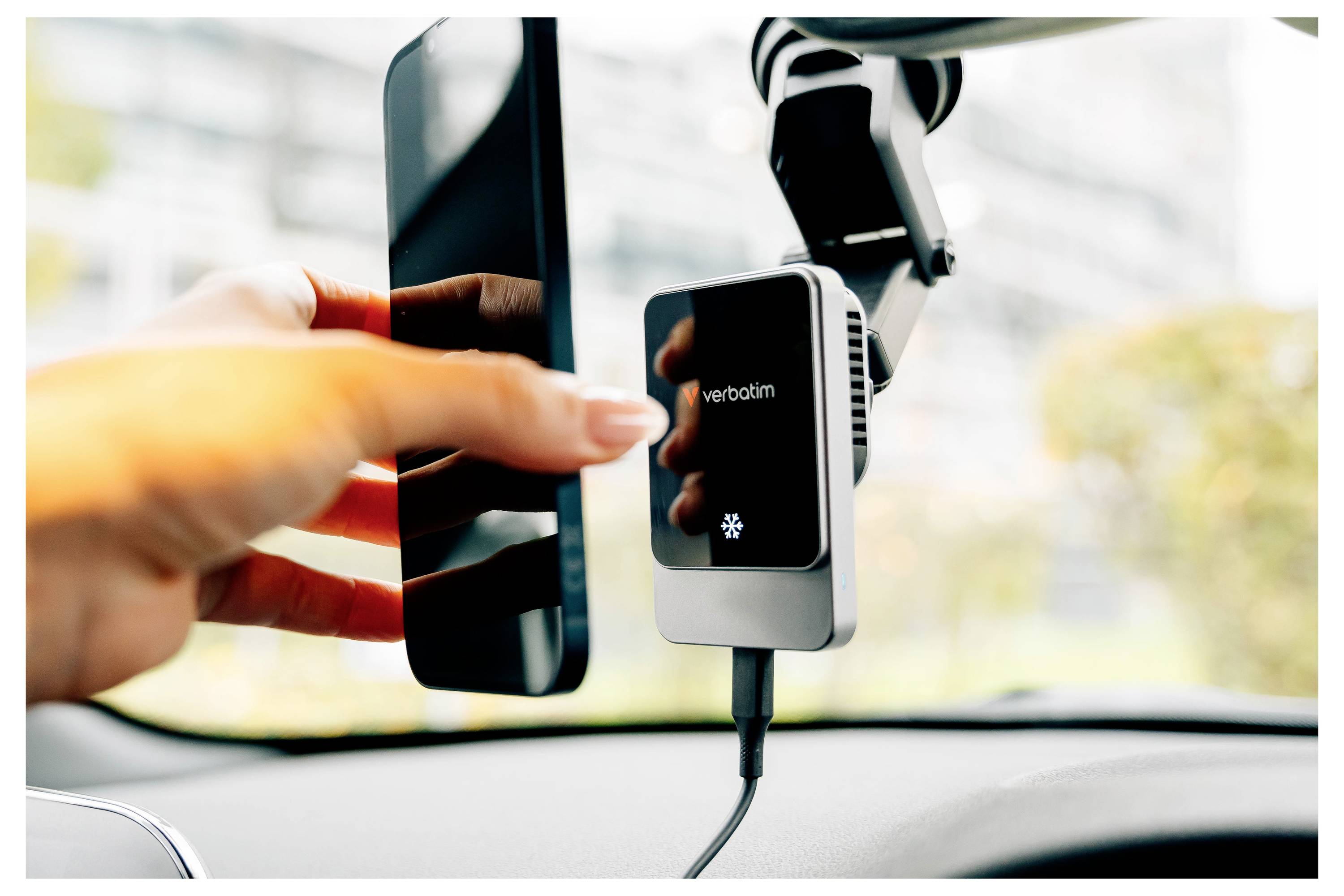 Eine Hand steckt ein Telefon in ein autofestes kabelloses Verbatim-Ladegerät neben der Windschutzscheibe.