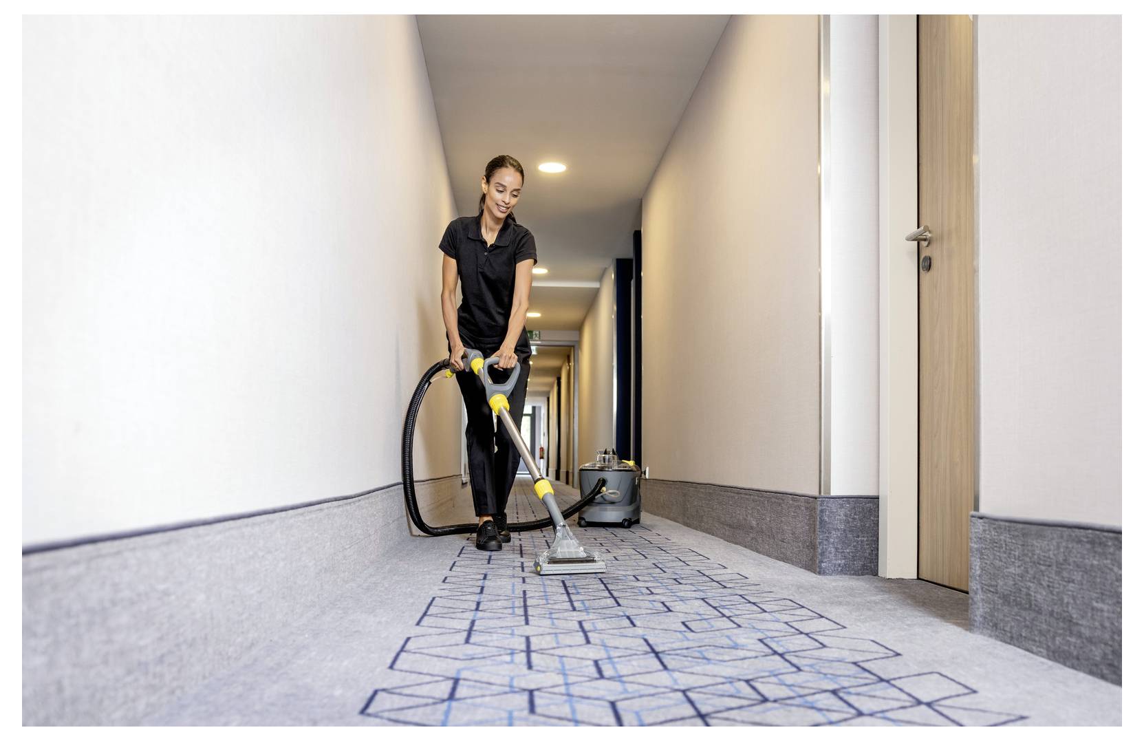 Eine Person, die einen Kärcher-Hochdruckreiniger verwendet, um einen großen Lastwagen in einer industriellen Garagenumgebung zu reinigen.