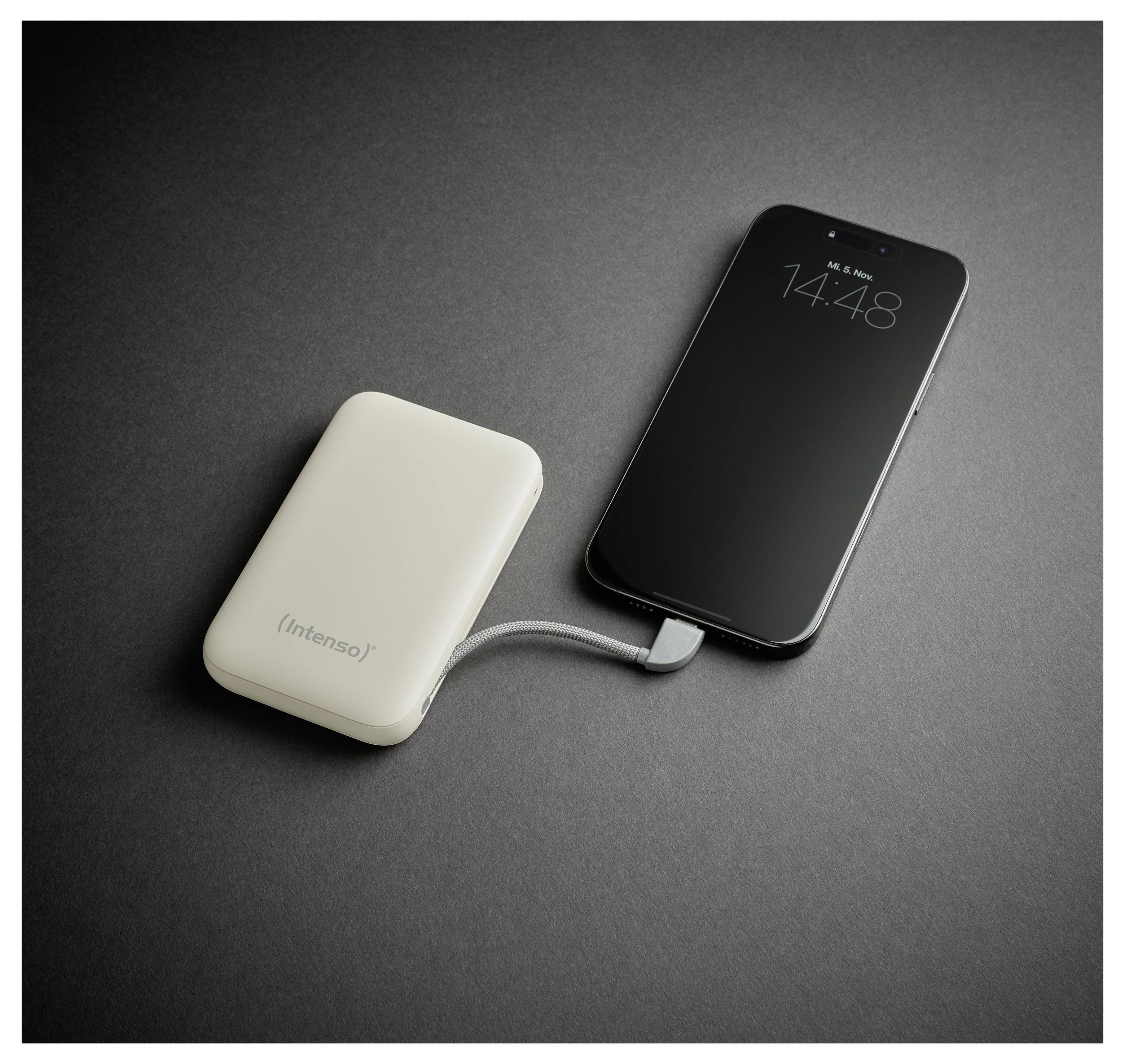 Ein Smartphone, das über ein Kabel mit einer tragbaren Powerbank verbunden ist, ruht auf einer dunklen Oberfläche. Der Telefonbildschirm zeigt die Uhrzeit 14:48 an.