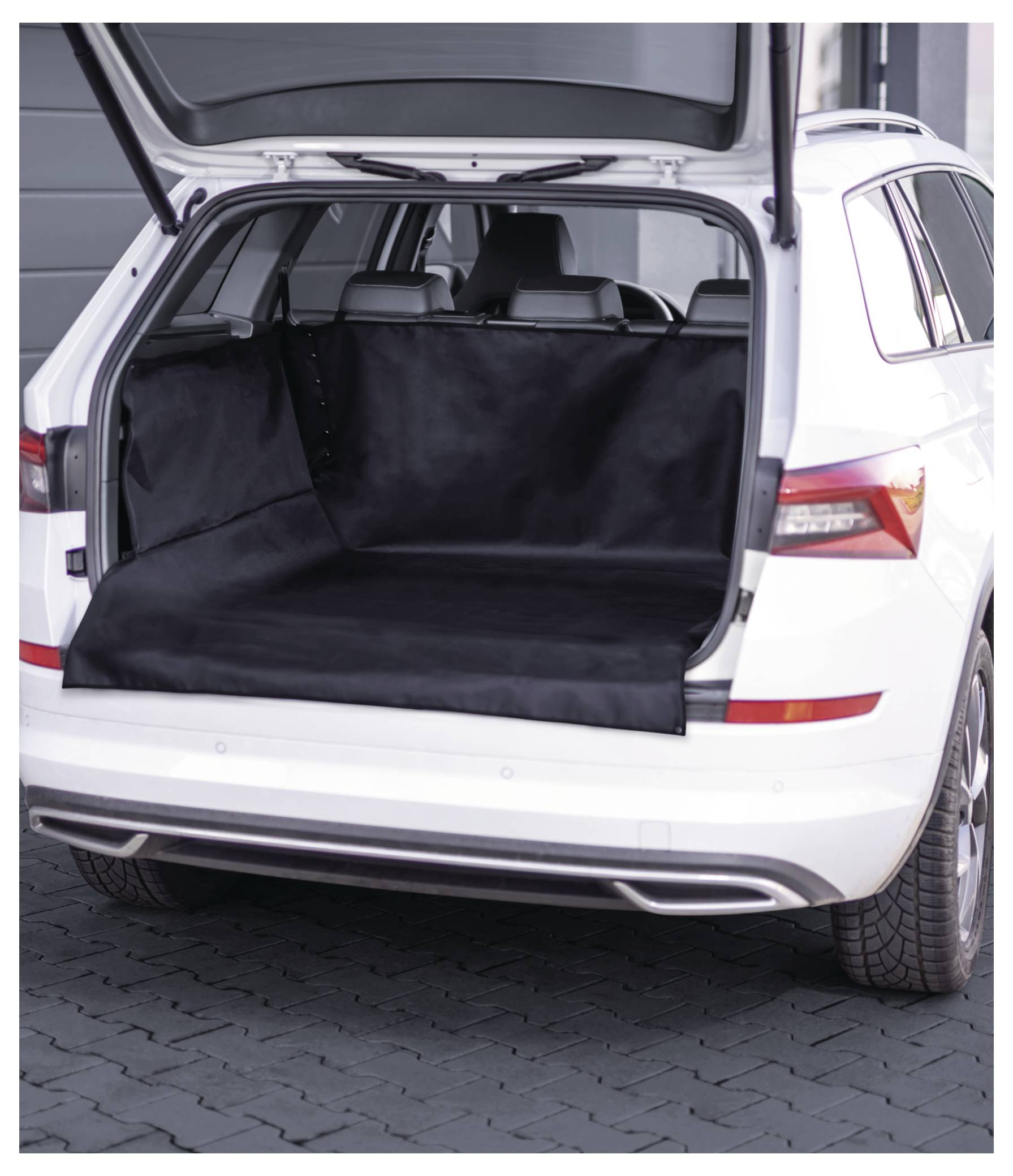 Ein weißes Auto mit offener Heckklappe, die mit einer schwarzen Schutzfolie ausgekleidet ist, auf einer gekachelten Oberfläche in einer städtischen Umgebung geparkt.