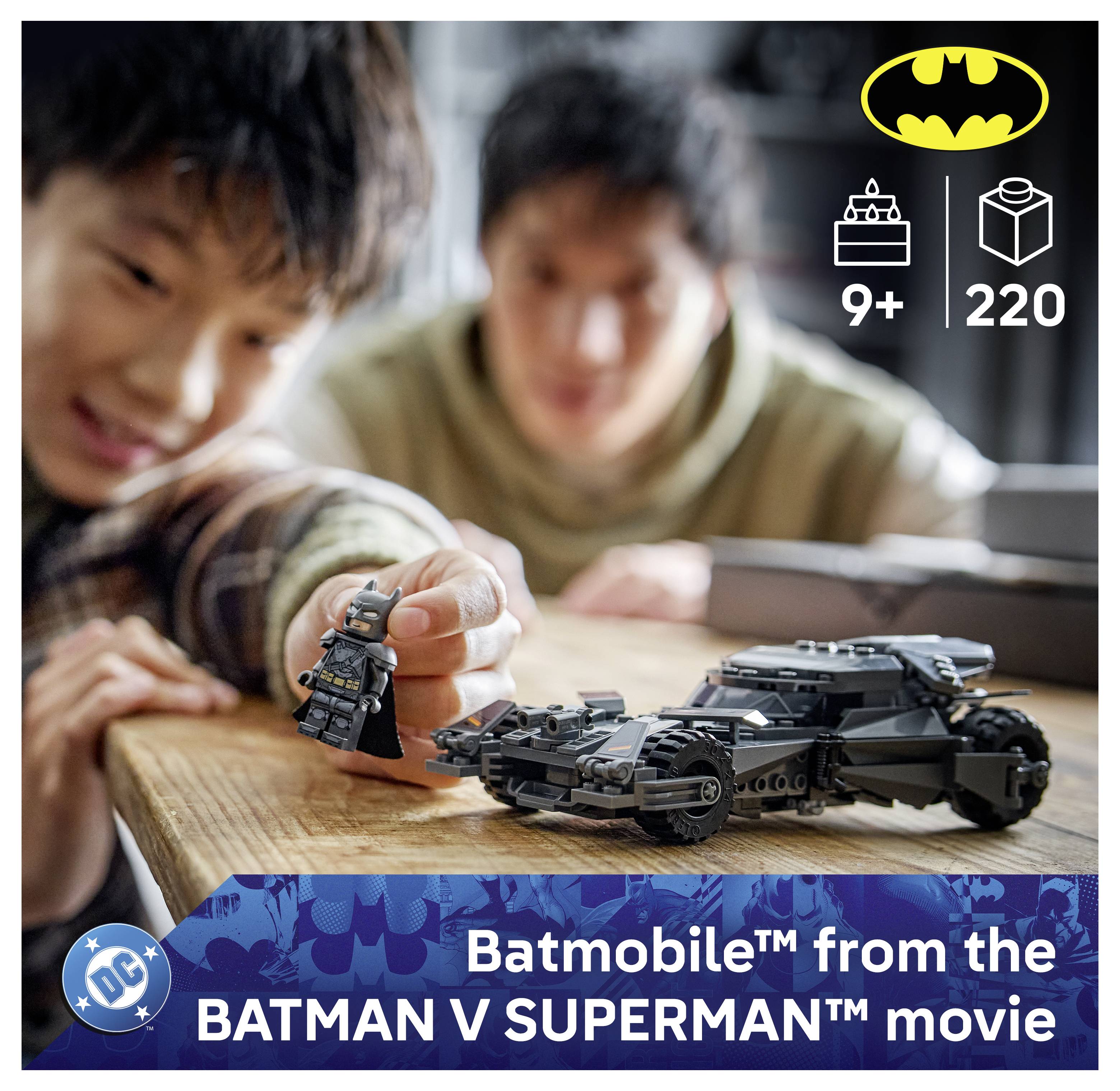 Ein Kind spielt mit einem Spielzeug-Batmobile und einer Batman-Figur. Der Überlagerungstext lautet „Batmobile aus dem Film BATMAN V SUPERMAN