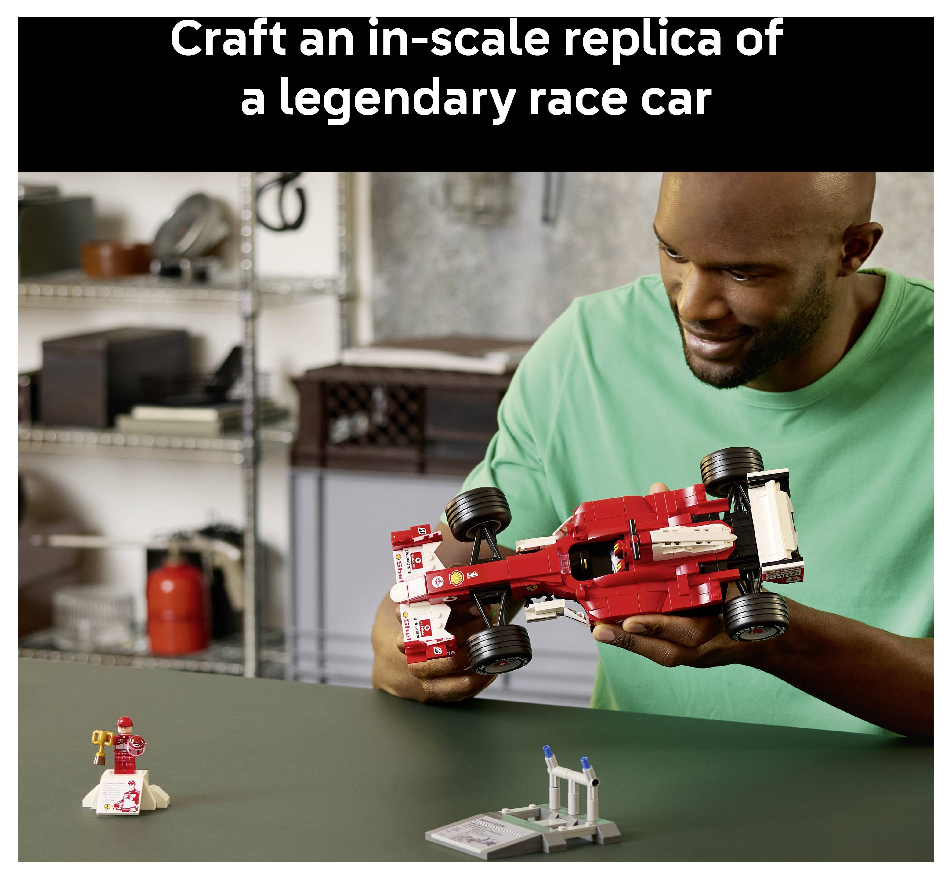 Eine Person in einem grünen Hemd montiert ein rotes Rennwagen-Modell in einer Werkstatt, mit dem Text „Fertigen Sie eine maßstabsgetreue Replik eines legendären Rennwagens