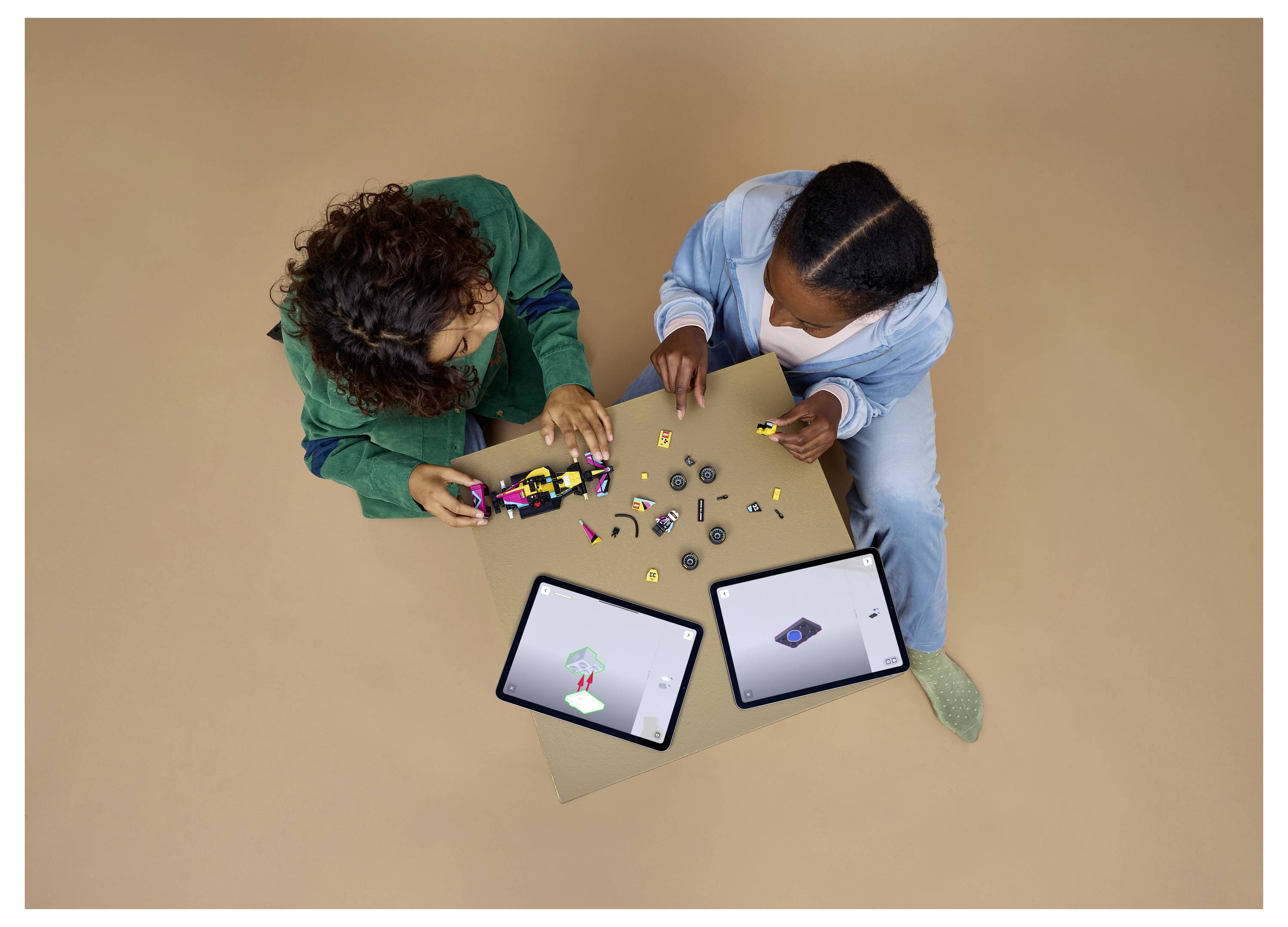 Zwei Personen montieren kleine Roboteile auf einer Platine, während sie sich dabei auf zwei elektronische Tablets neben ihnen beziehen.