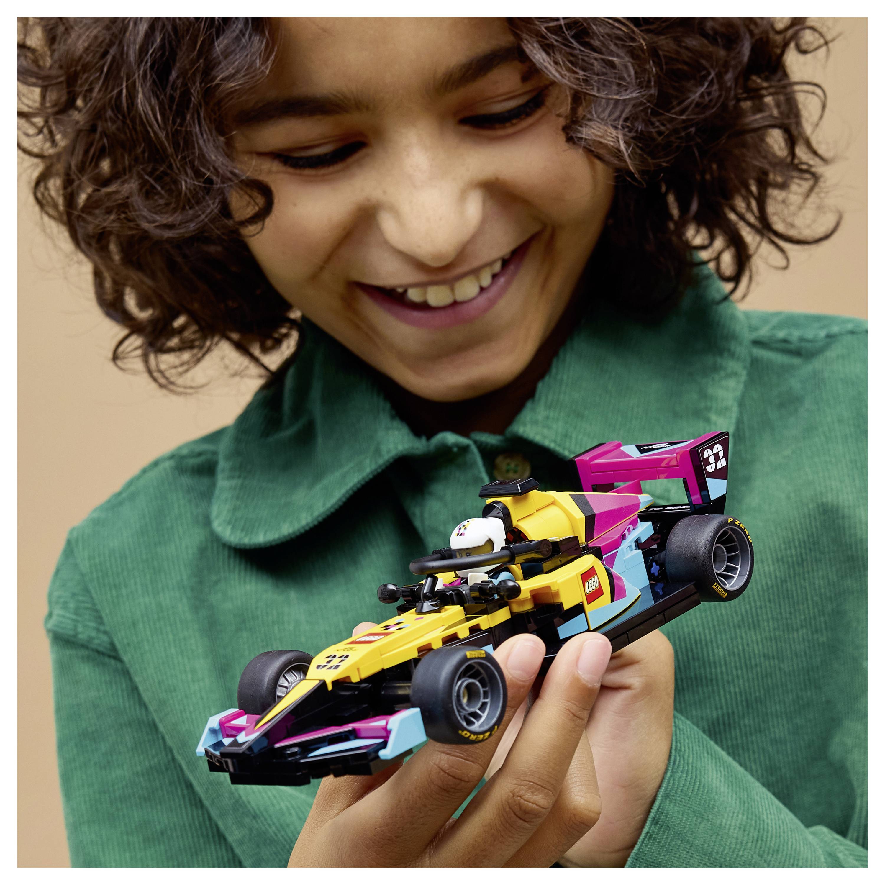 Ein Kind hält ein buntes Spielzeug-Rennwagen in den Händen, lächelt voller Freude und schaut auf das detailreiche Modell, das es in den Händen hält.