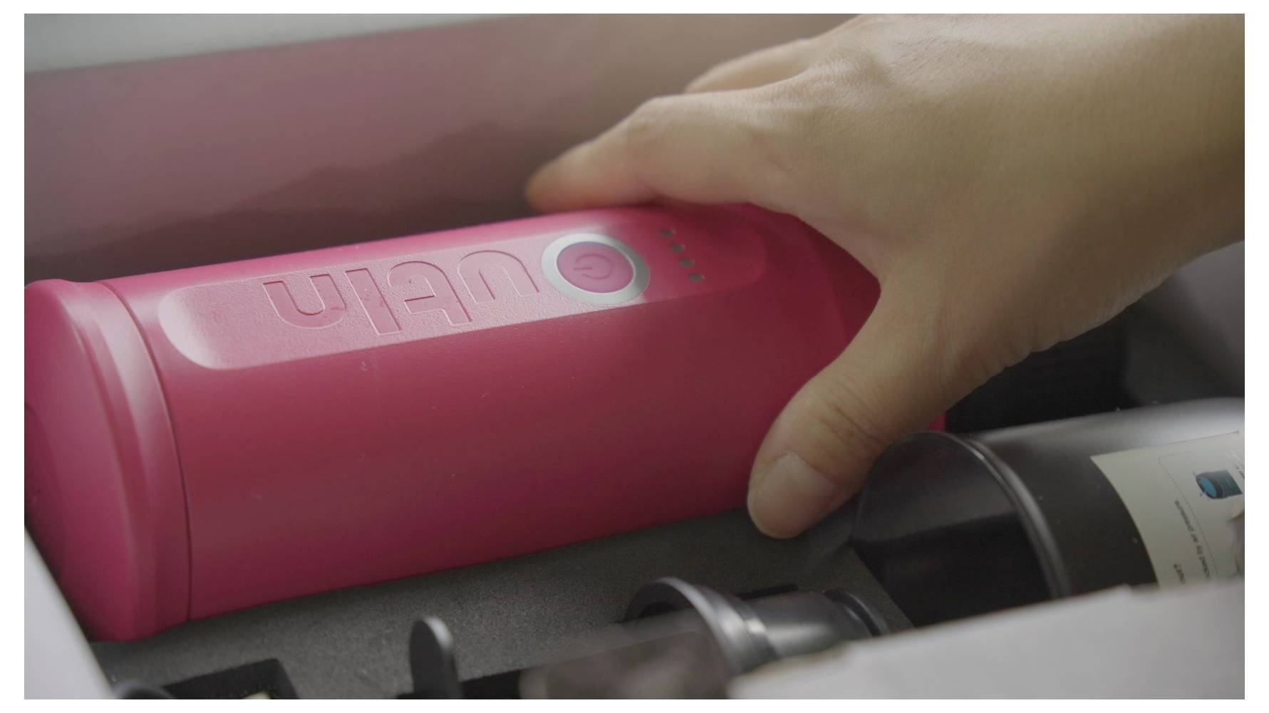 Eine Person, die nach einem rosa zylindrischen Objekt greift, das mit „Ulan