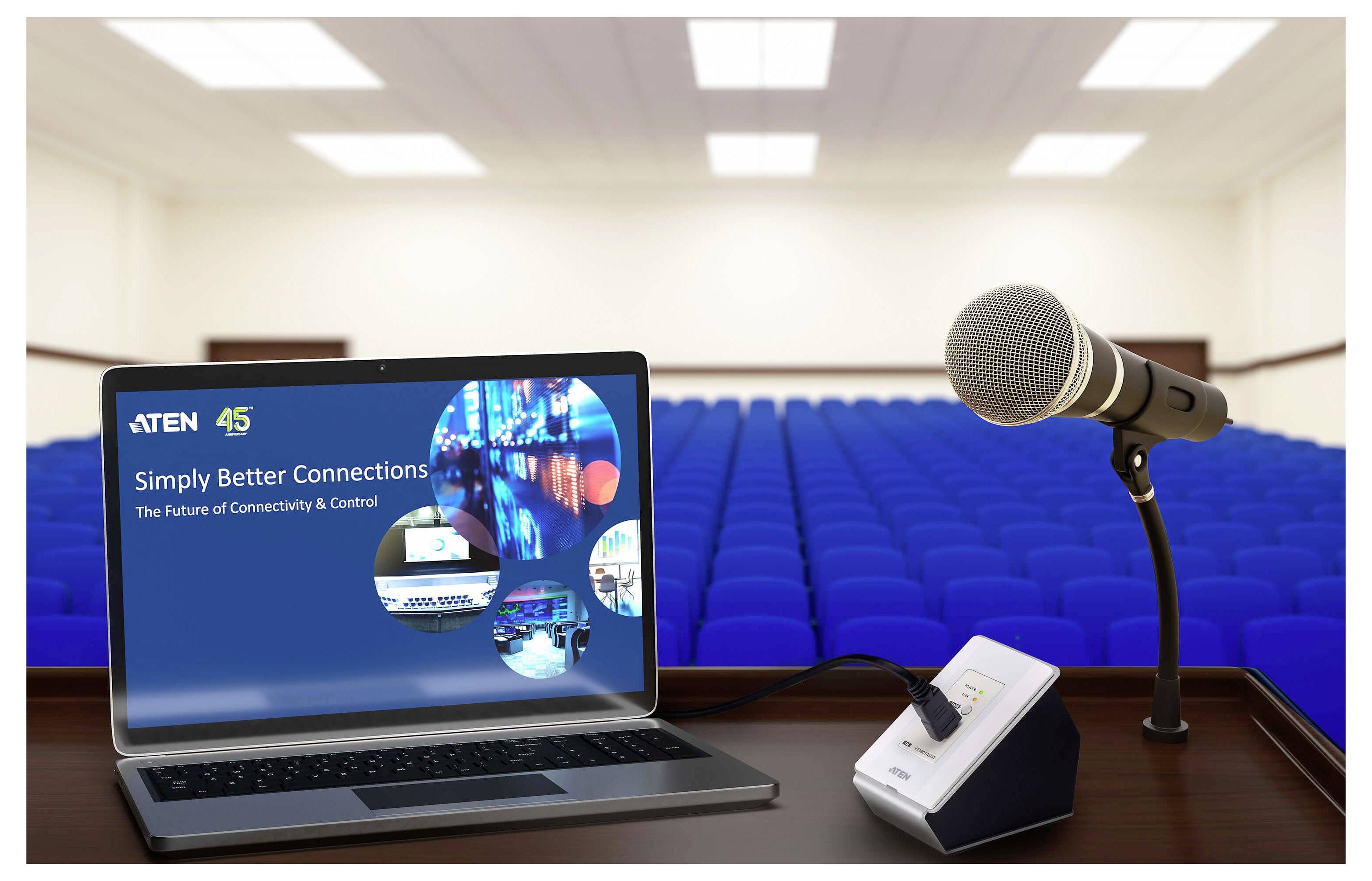 Ein Laptop, der auf einem Podium neben einem Mikrofon in einem leeren Auditorium den Text 