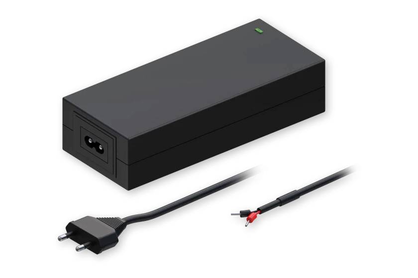 Ein schwarzer Stromadapter mit grüner Anzeigelampe wird gezeigt. Er verfügt über einen zweipoligen Stecker und ein Kabel mit freigelegten roten und schwarzen Drähten am Ende.