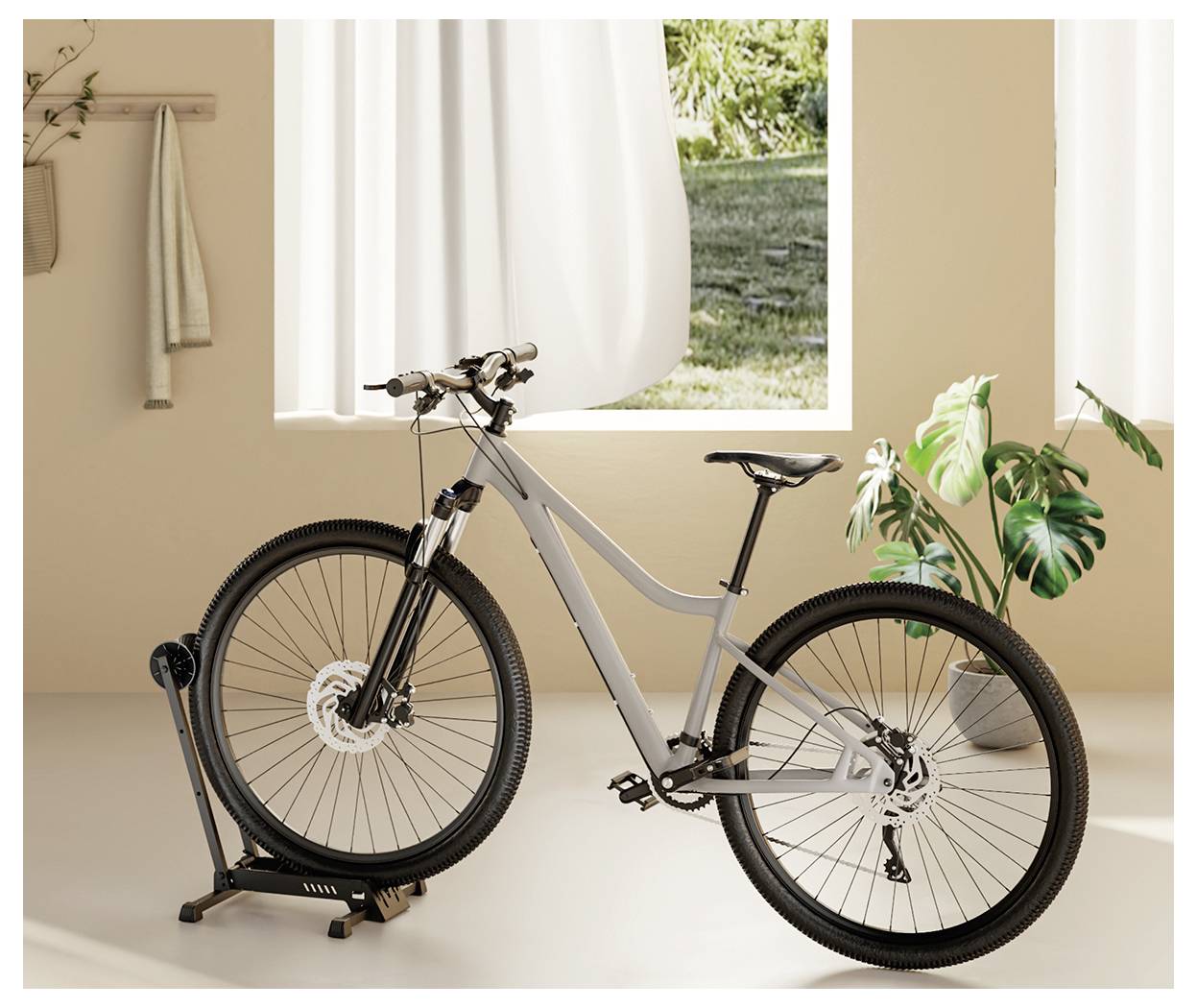Ein schlankes graues Rennrad, das auf einem Indoor-Trainingsständer in einem warm beleuchteten Raum mit einer blattreichen Pflanze und einem Fenster mit Grün draußen montiert ist.