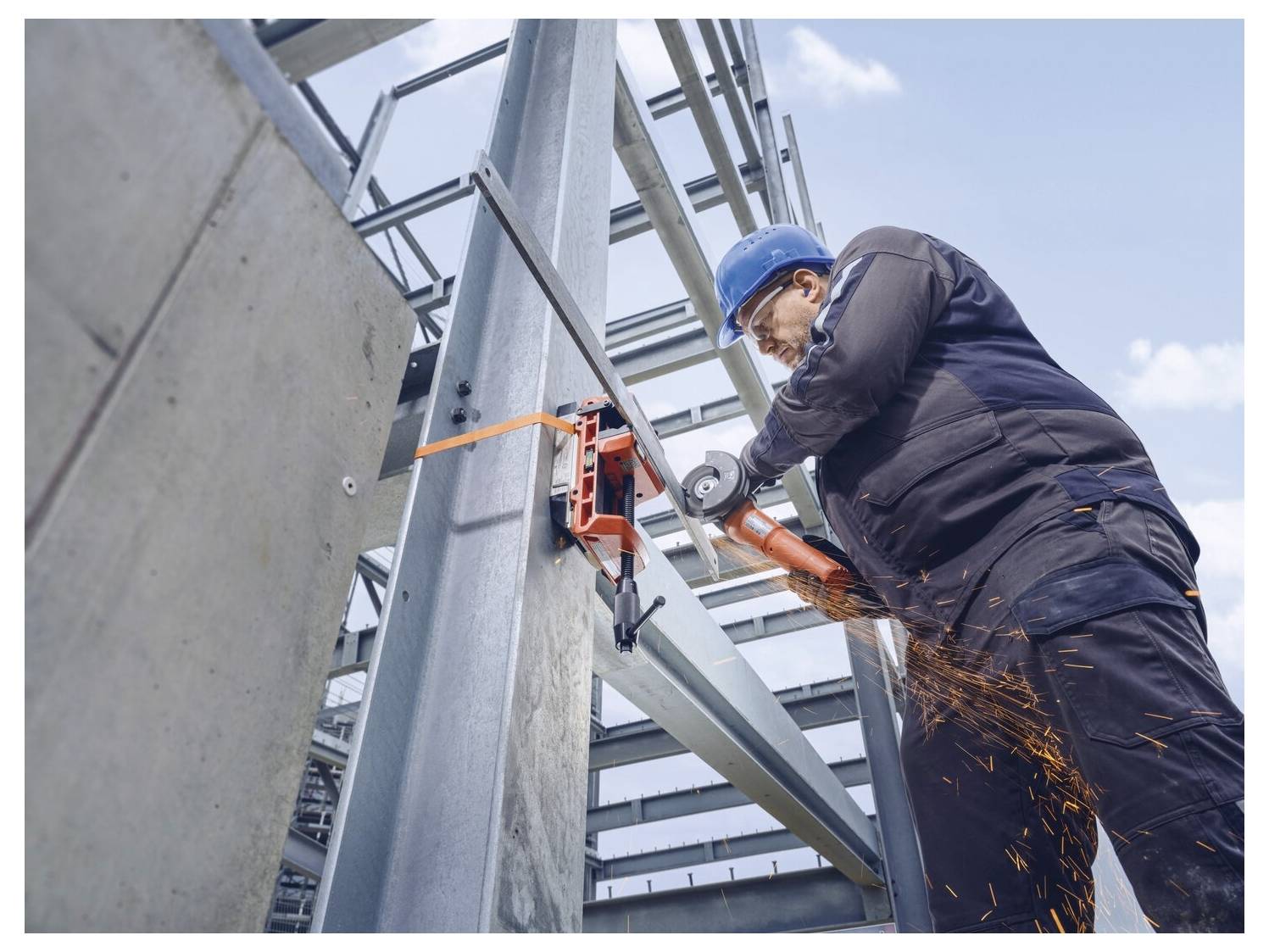 Ein Bauarbeiter mit blauem Helm und Schutzausrüstung nutzt einen Schleifer zum Schneiden von Metallträgern, wobei Funken fliegen.