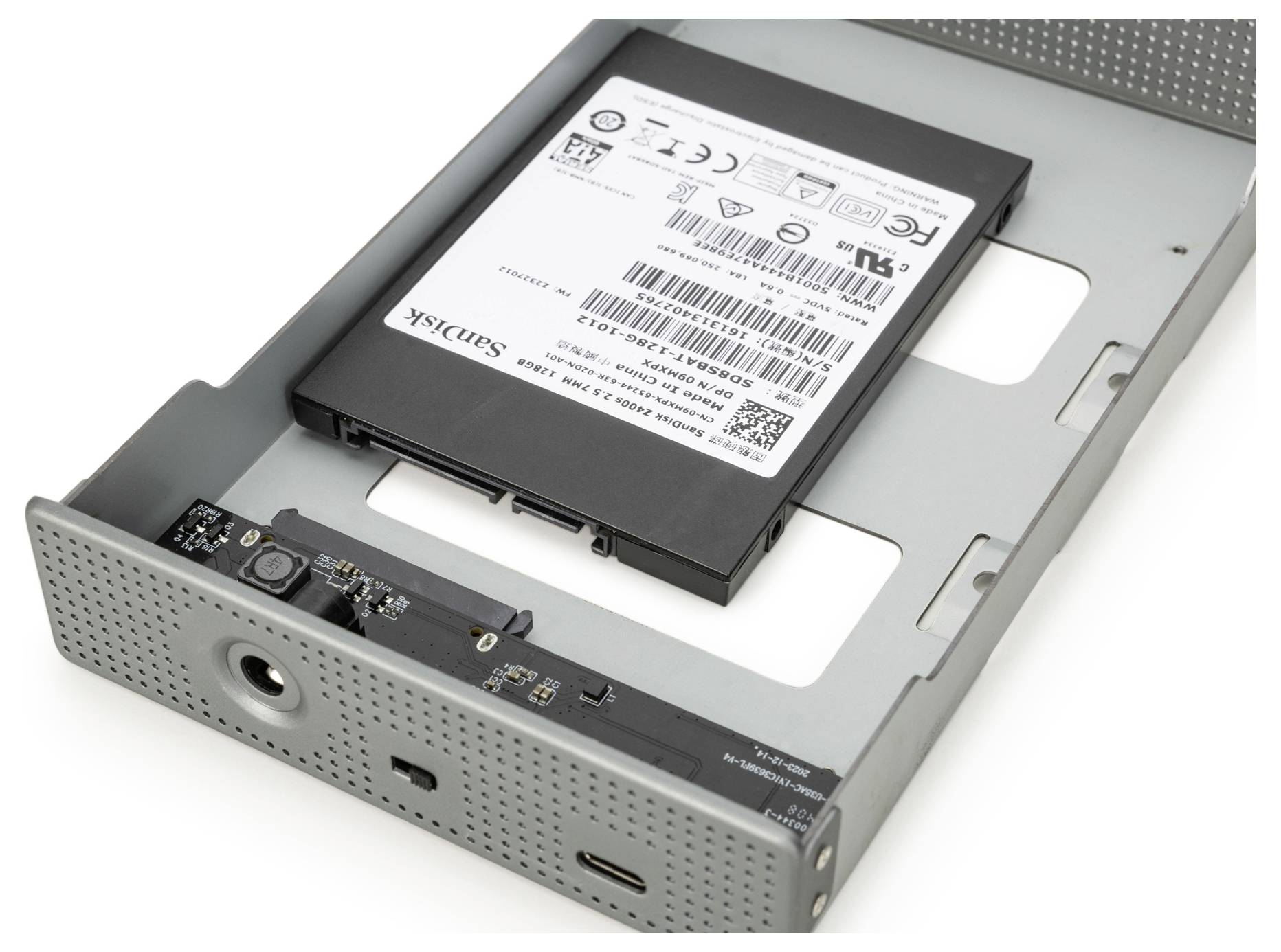 Offenes Metall-Festplattengehäuse mit einer SanDisk SSD im Inneren, das USB-C- und USB-A-Anschlüsse auf dem Panel zeigt.