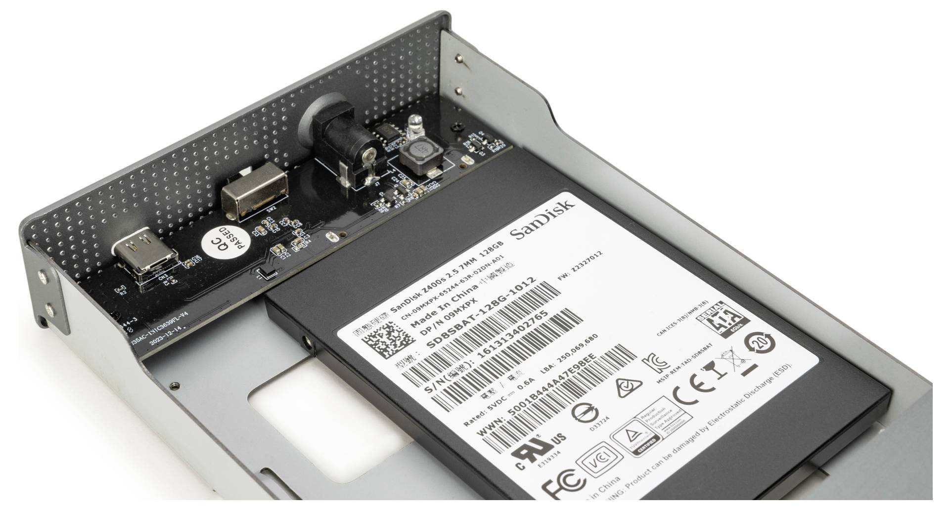 Offene Festplattengehäuse mit sichtbarer Leiterplatte und einer montierten SanDisk-SSD, mit verschiedenen Anschlüssen und Verbindern.