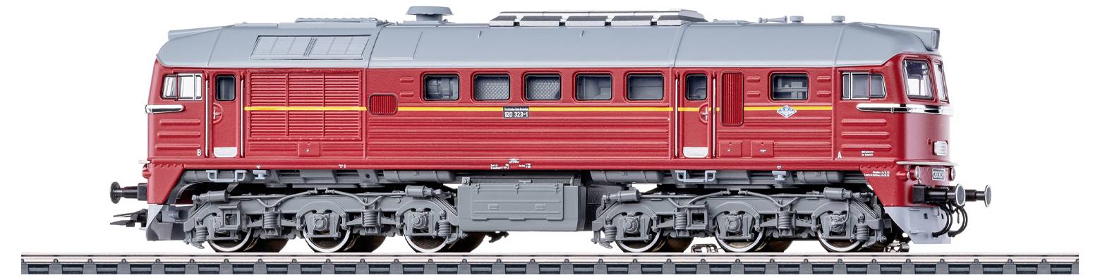 Eine rot und grau gefärbte Modelleisenbahn-Lokomotive auf einem Gleis, mit mehreren Fenstern und detaillierten Rädern, von der Seite betrachtet.