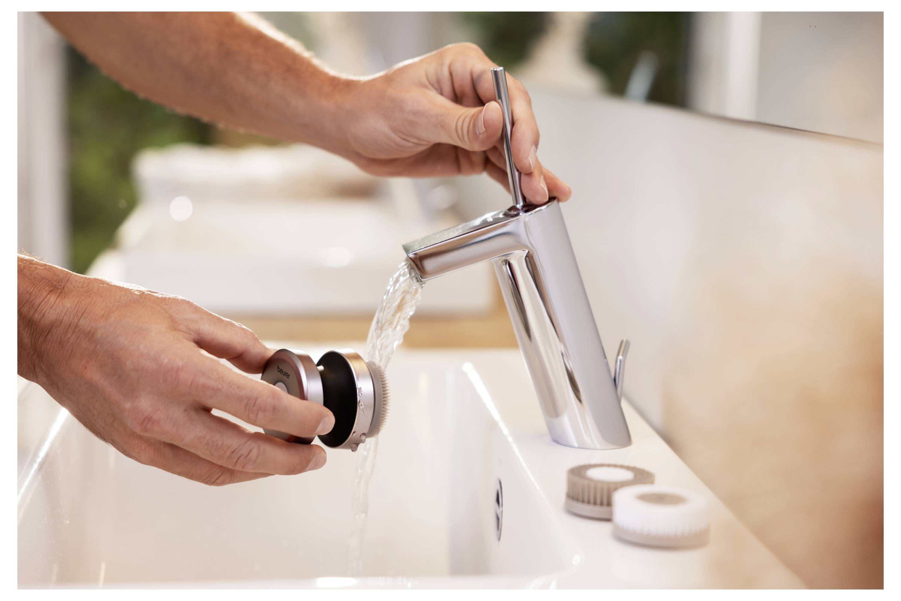 Eine Person reinigt ein Badezimmer-Abflusssieb unter einem modernen Chromwasserhahn mit fließendem Wasser, was auf Wartung oder Reinigung hindeutet.