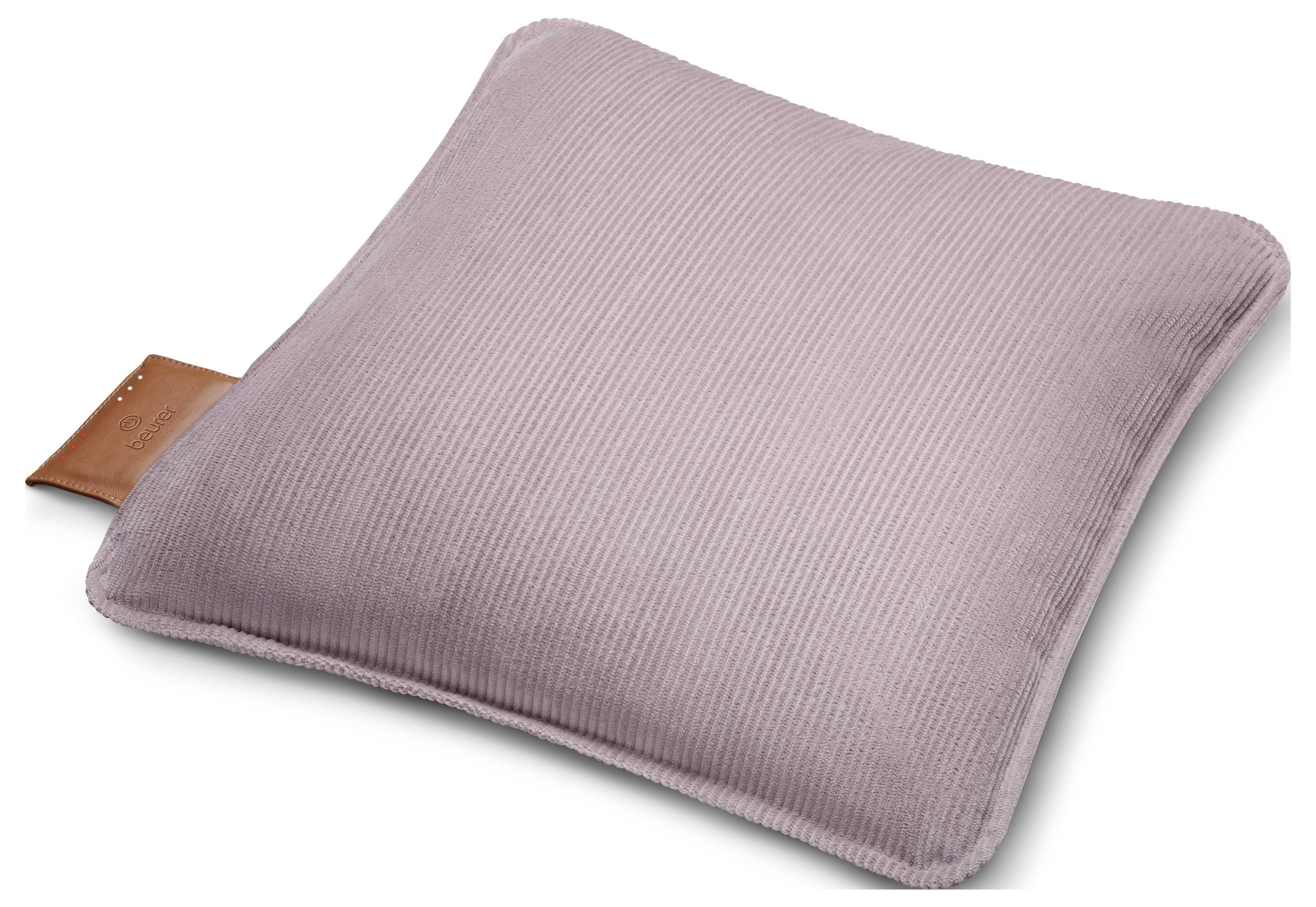 Ein weiches, quadratisches, malvenfarbenes Kissen mit strukturierter, gerippter Oberfläche und einem kleinen braunen Lederanhänger an der Seite, gezeigt vor weißem Hintergrund.