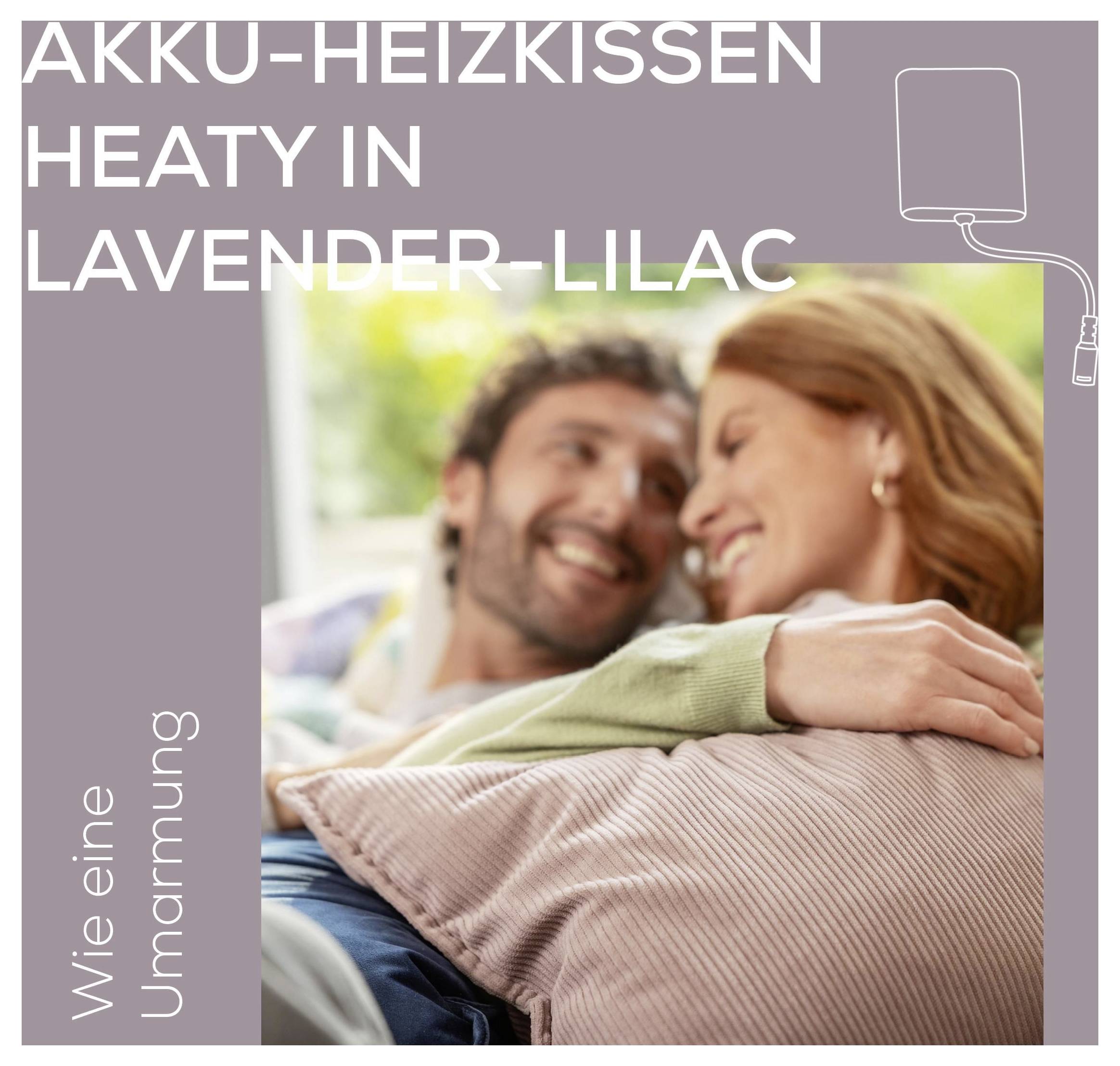 Ein Paar lächelt und entspannt sich auf einem Sofa mit einem lavendelfarbenen Wärmekissen. Text: „Heaty in Lavender-Lilac