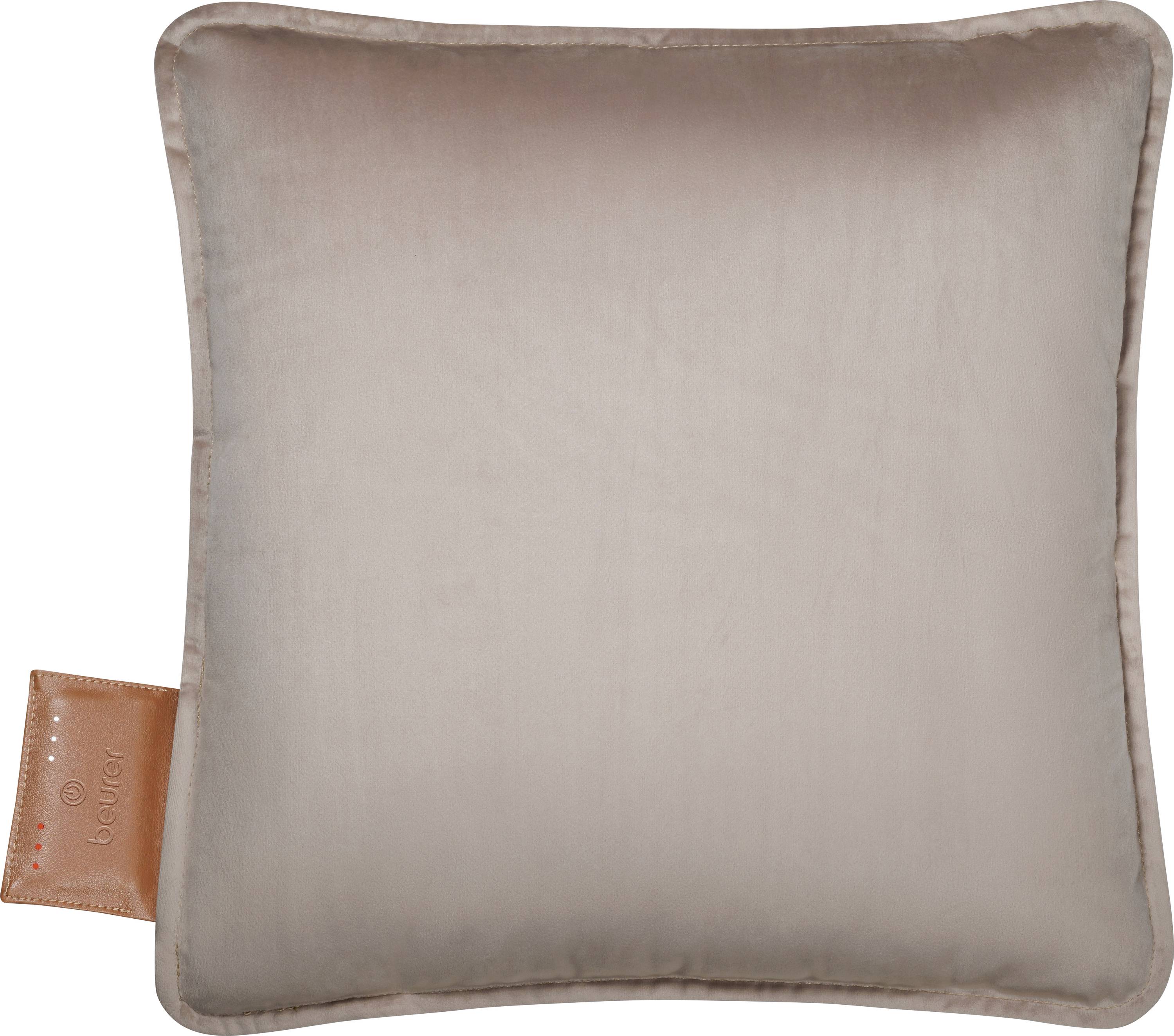 Ein quadratisches taupefarbenes Kissen mit subtilen Glanz und einem braunen Lederetikett an der Seite, auf dem das Wort 