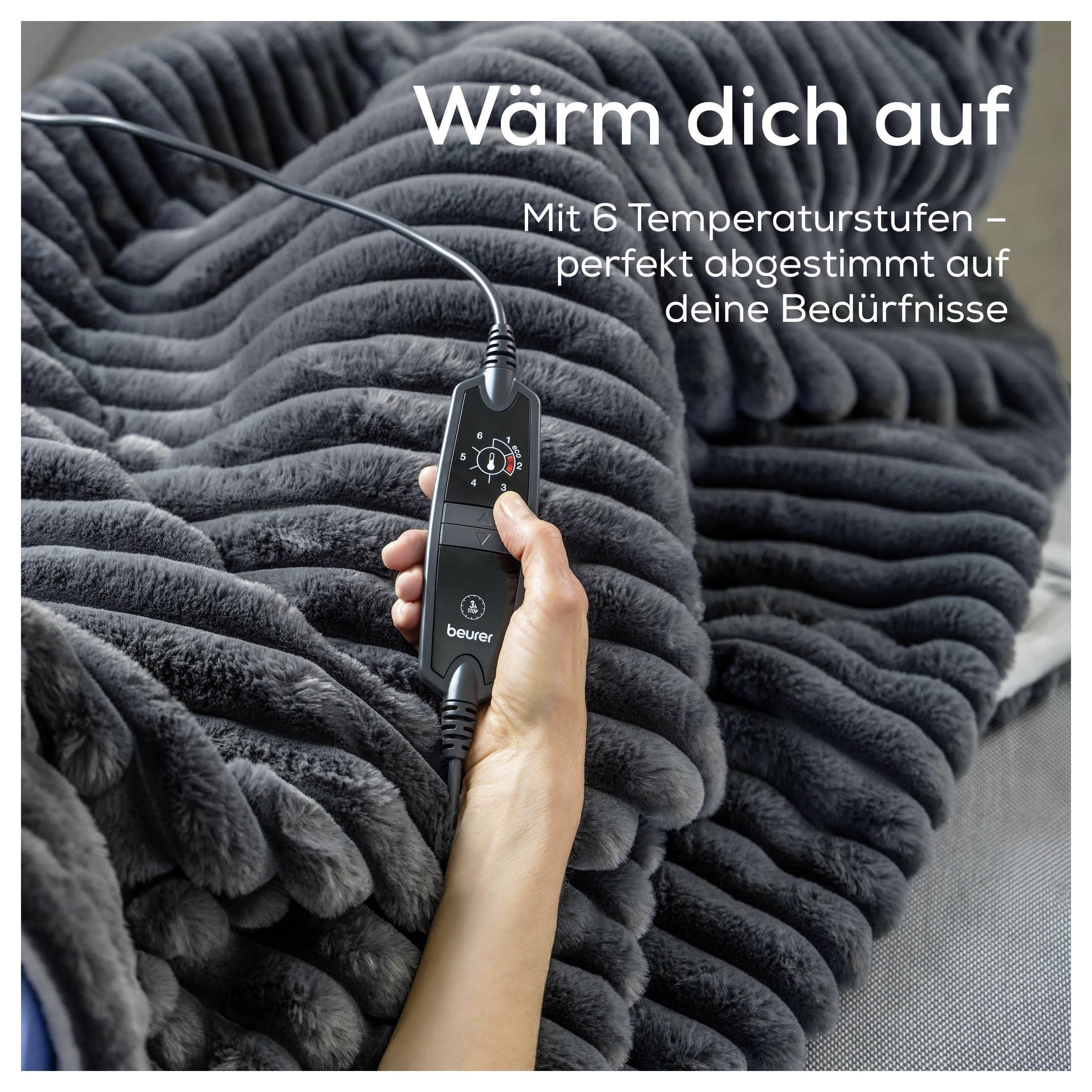 Eine Hand hält eine Fernbedienung für eine elektrische Wärmdecke mit dem Text „Wärm dich auf. Mit 6 Temperaturstufen – perfekt abgestimmt auf deine Bedürfnisse.