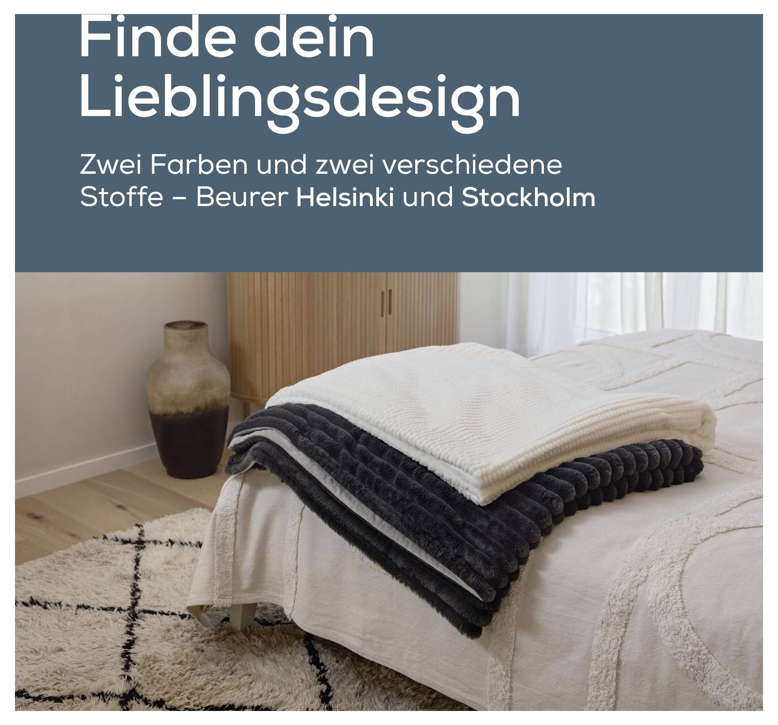 Ein ordentlich gemachtes Bett mit gefalteten beigen und dunkelgrauen Decken in einer gemütlichen Schlafzimmereinrichtung, mit einem Holzschrank und einer dekorativen Vase.