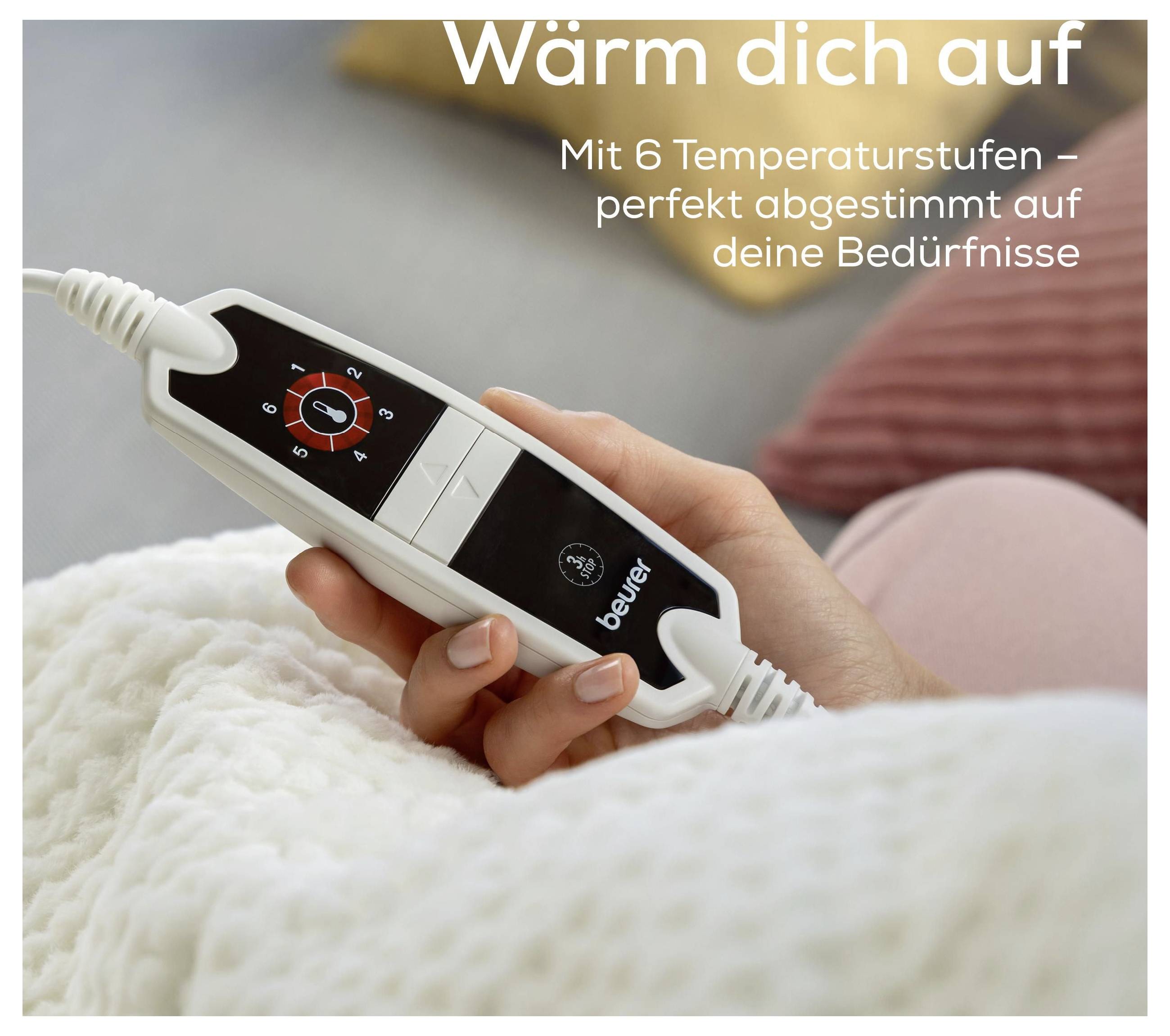 Eine Hand hält eine Wärmekissen-Fernbedienung mit Text „Wärm dich auf. Mit 6 Temperaturstufen - perfekt abgestimmt auf deine Bedürfnisse.