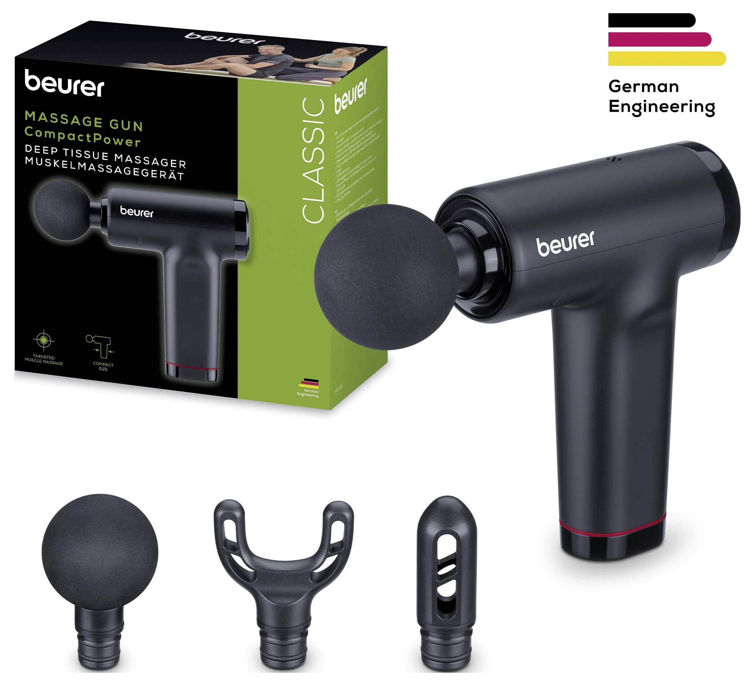 Eine schwarze Massagepistole mit drei Aufsätzen wird gezeigt. Die Verpackung im Hintergrund hebt 