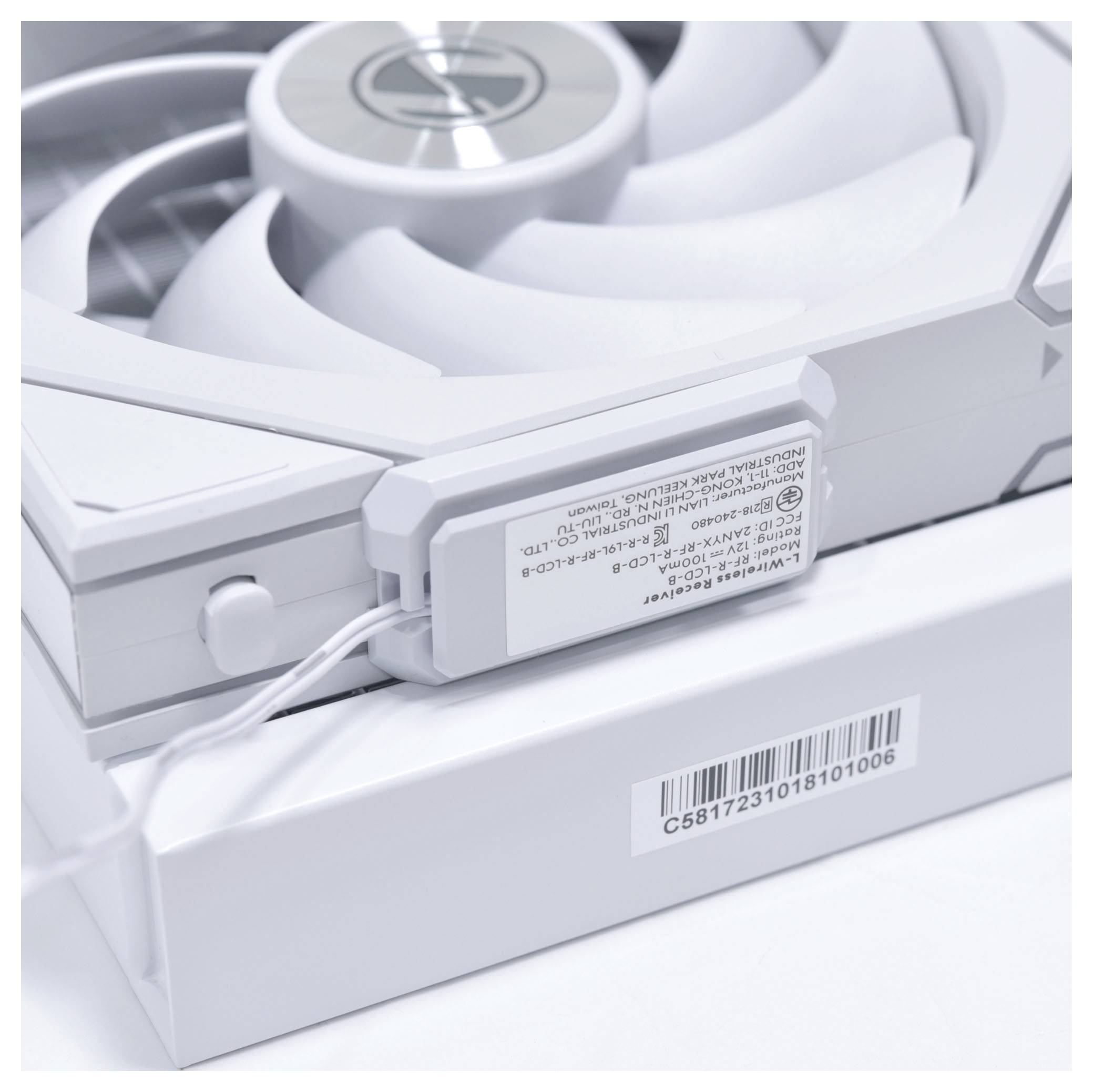 Ein Nahaufnahmebild eines weißen Computerlüfters, das seine inneren Flügel und ein Etikett mit Text und einem Barcode zeigt, wobei das Modell des Lüfters hervorgehoben wird.