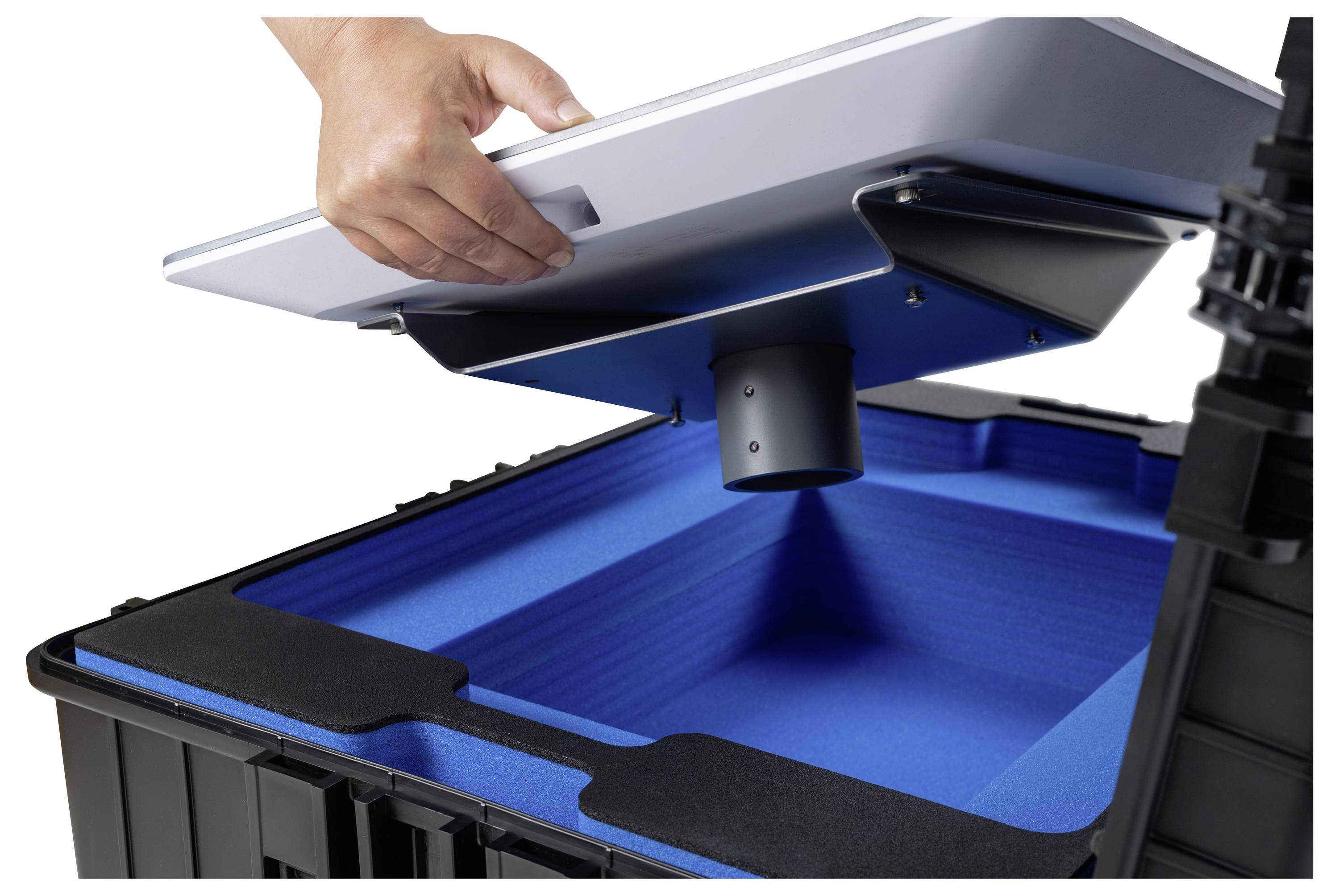 Eine Person setzt einen Deckel mit einer belüfteten Vorrichtung auf einen großen schwarzen Behälter, der mit blauem Schaumstoff ausgekleidet ist, was auf einen Lager- oder Transportzweck hindeutet.