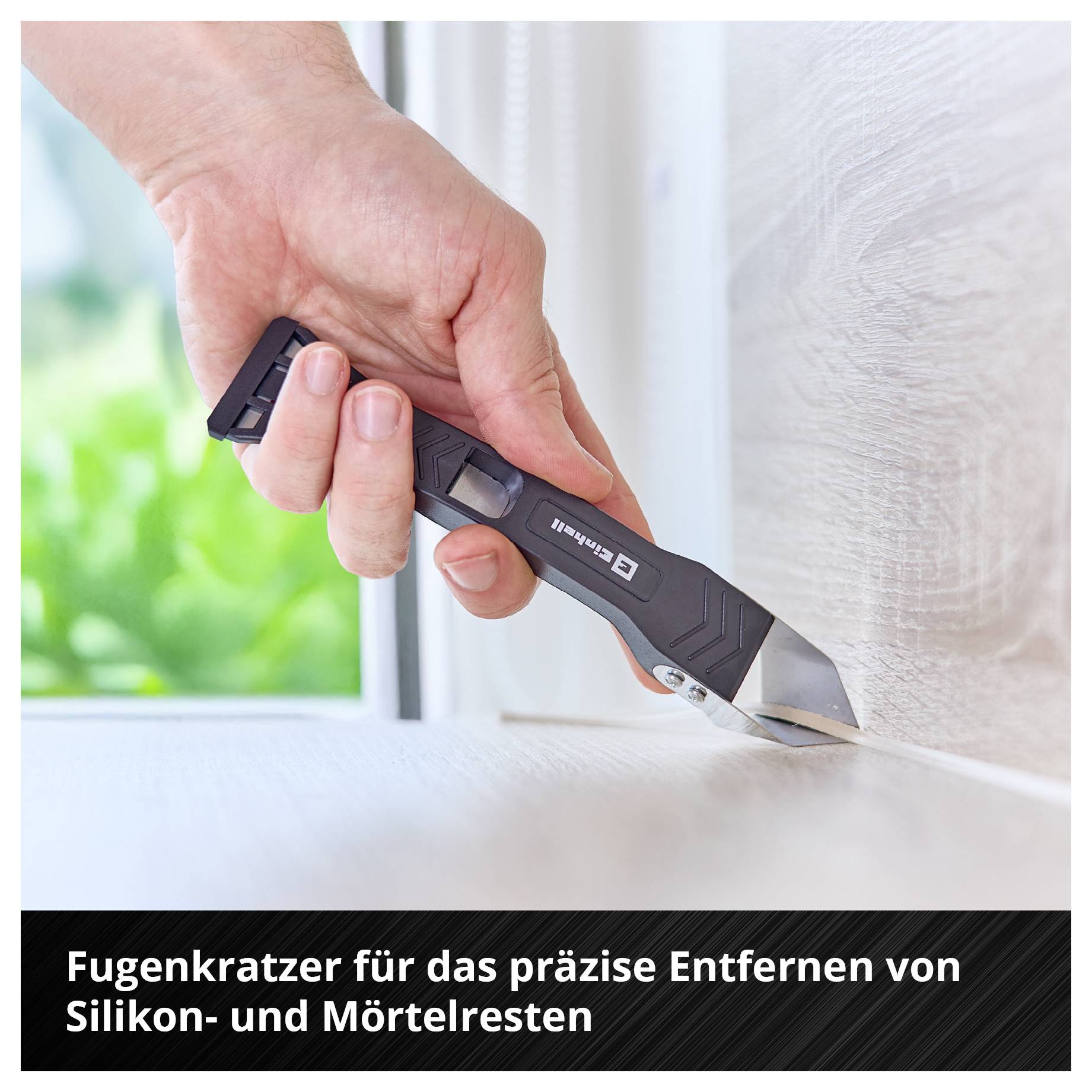 Hand hält Fugenkratzer und entfernt Silikon- und Mörtelreste von einer Kante.