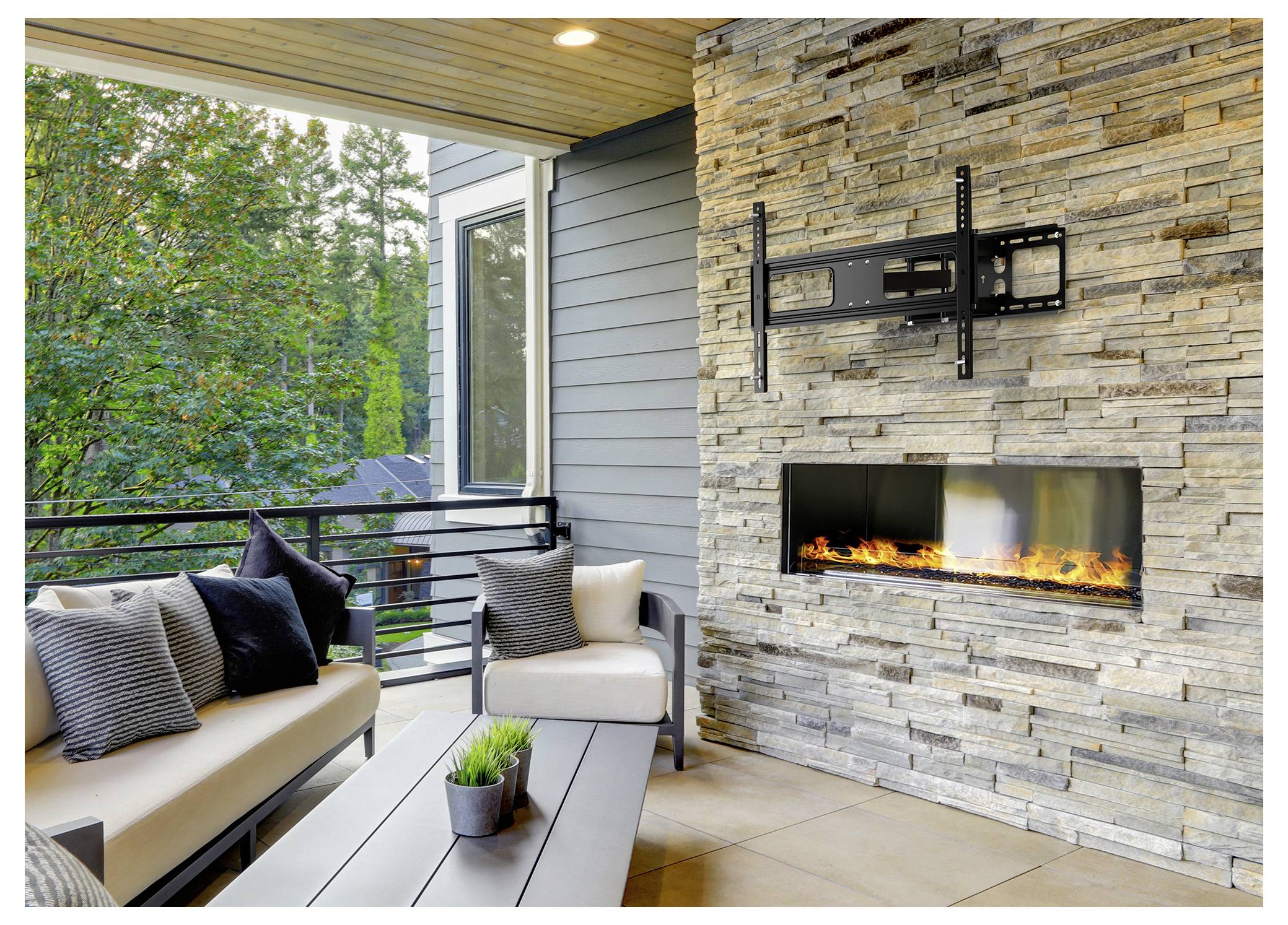 Outdoor-Terrasse mit Steinkamin, gepolsterten Sitzmöbeln und Tisch. Grünflächen, die durch Geländer sichtbar sind, verstärken die gemütliche Atmosphäre.