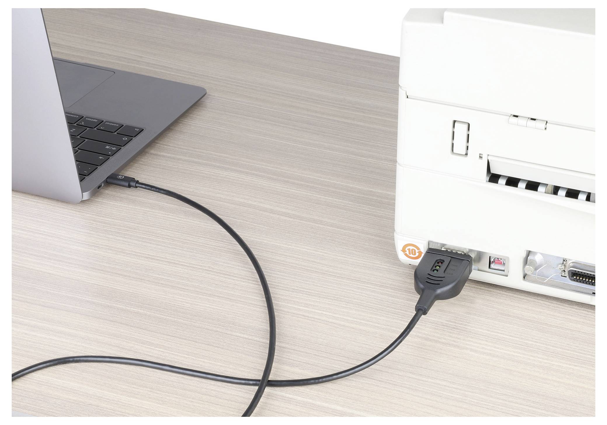 Ein Laptop ist über ein Kabel mit einem Drucker verbunden, der sich auf einem Holzschreibtisch befindet und zeigt eine Druckeinrichtung.
