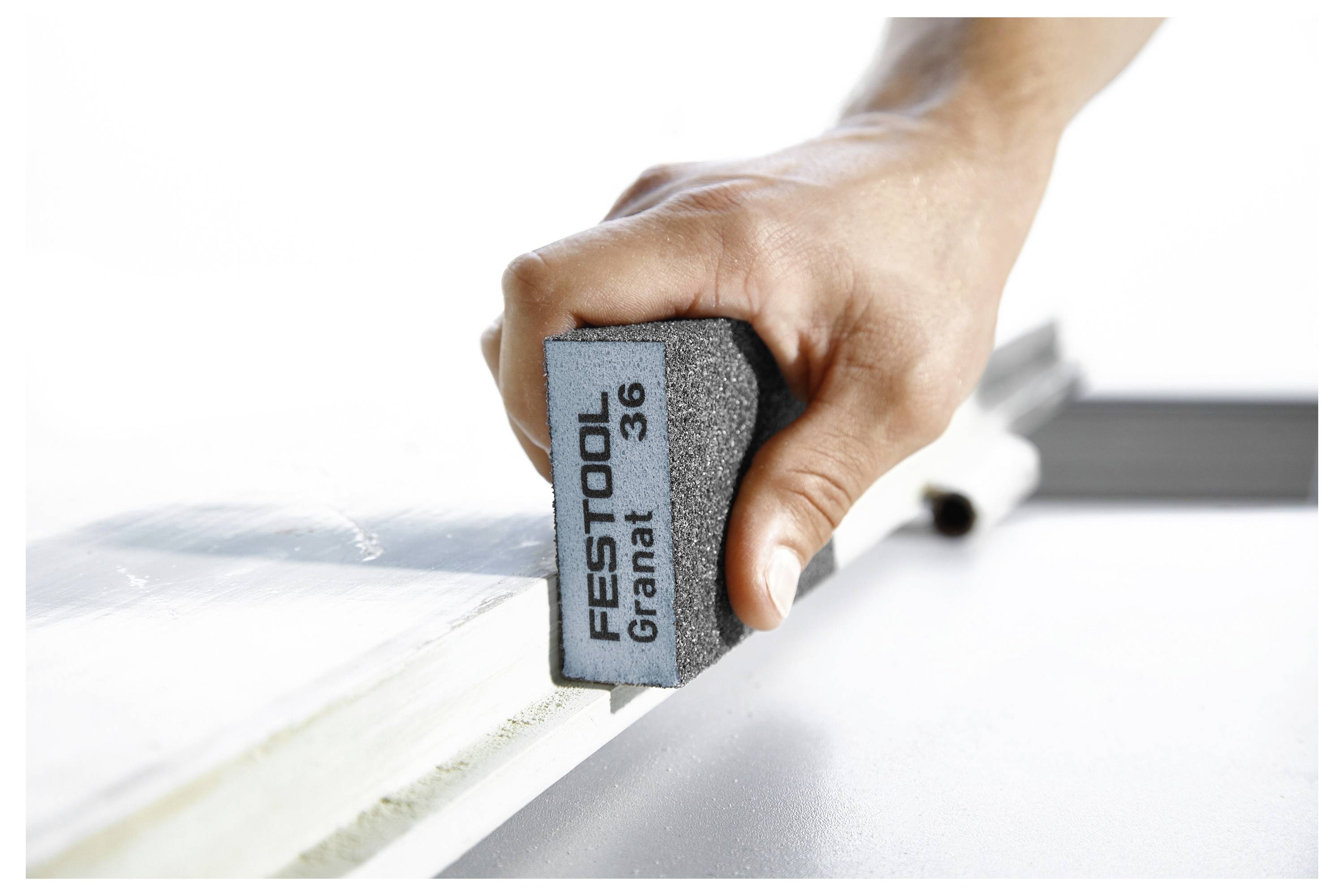 Eine Person bereitet eine Schleifmaschine vor, indem sie Schleifpapier in einer Werkstattumgebung anbringt und dabei Werkzeuge und praktische Handgriffe hervorhebt.