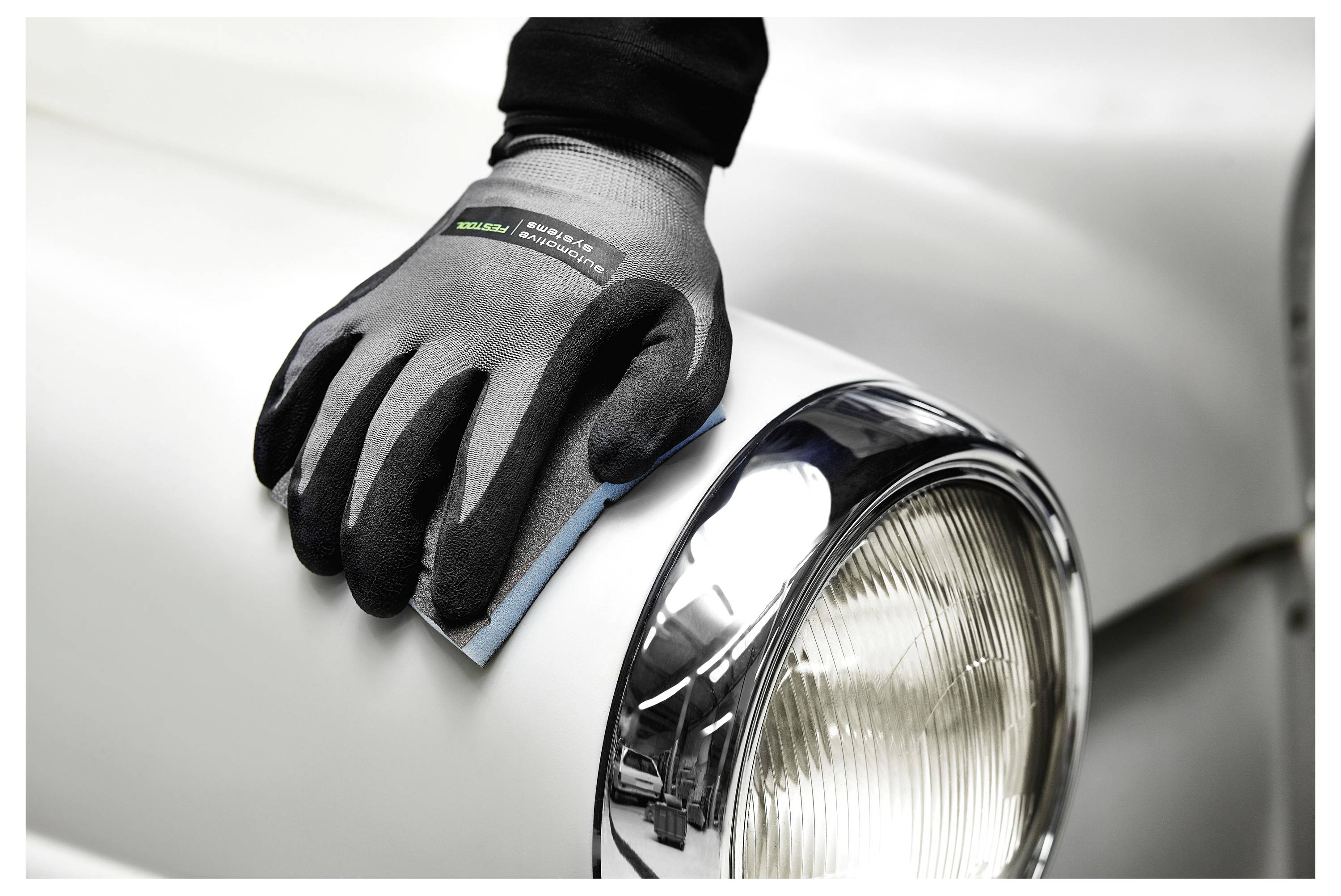 Eine behandschuhte Hand poliert ein Oldtimer-Scheinwerfer und verstärkt dessen Glanz und Klarheit.