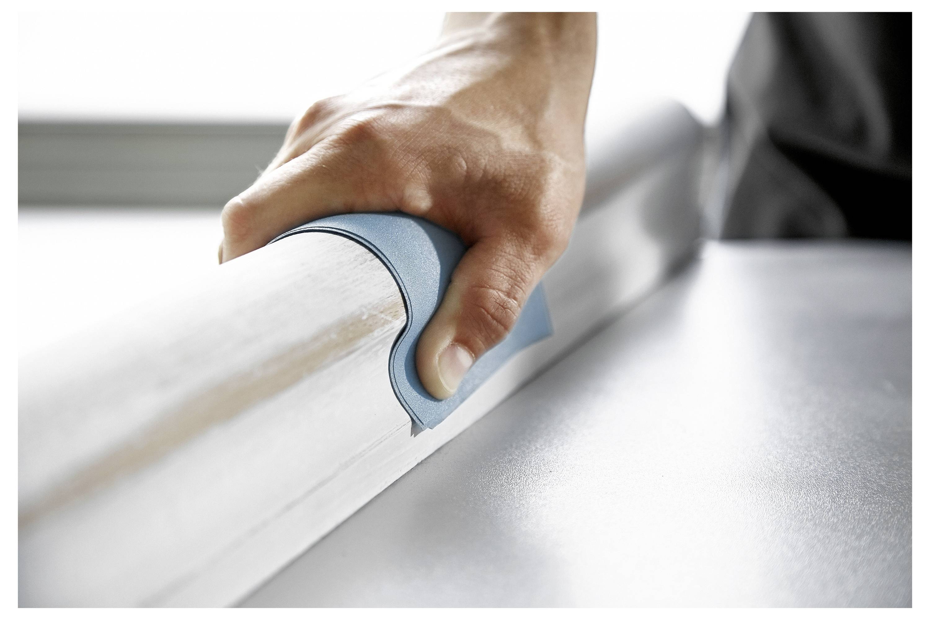 Eine Hand nutzt Schleifpapier, um eine Holzoberfläche zu glätten, wobei handwerkliches Geschick und der Holzbearbeitungsprozess hervorgehoben werden.