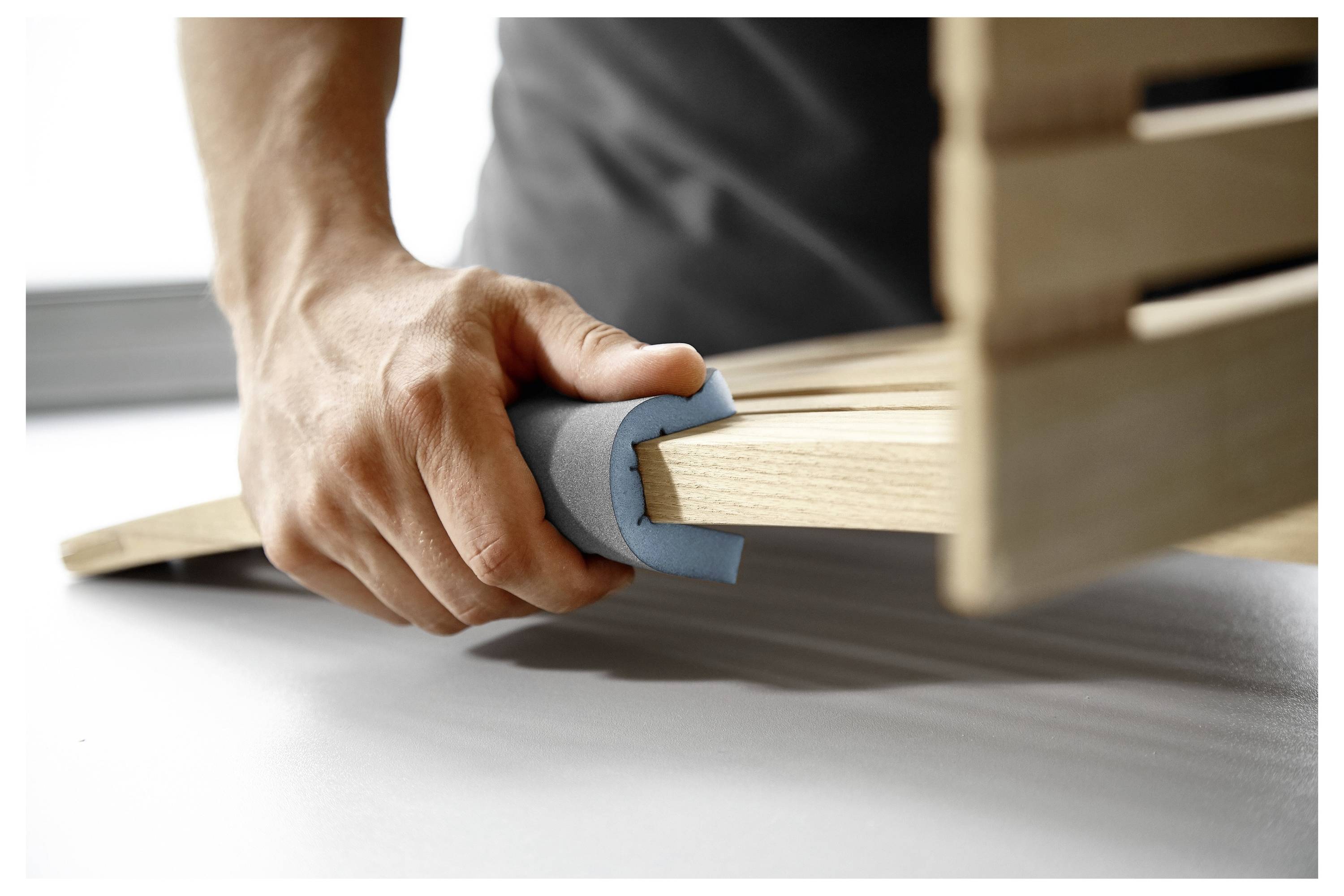 Person, die Holzleisten zusammensetzt und Schaumstoffecken zum Schutz verwendet.