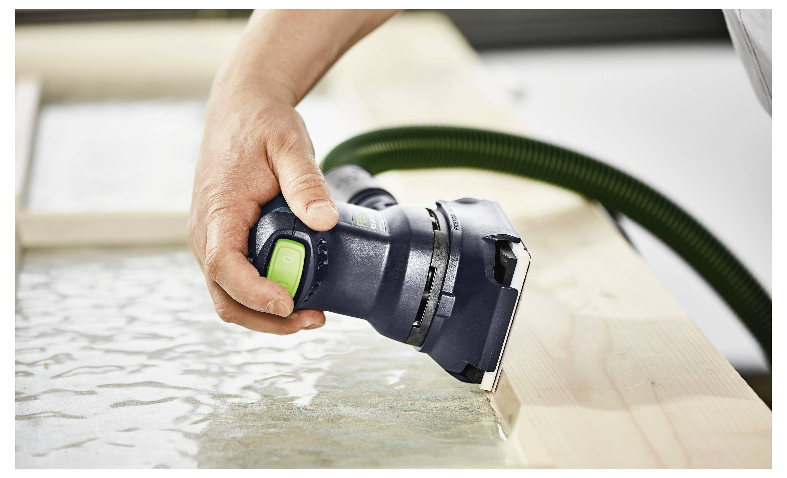 Eine Person hält einen Elektroschleiffer und eine Schutzvorrichtung, während sie eine Holzoberfläche glättet, mit Fokus auf Handwerkskunst und Sicherheit.