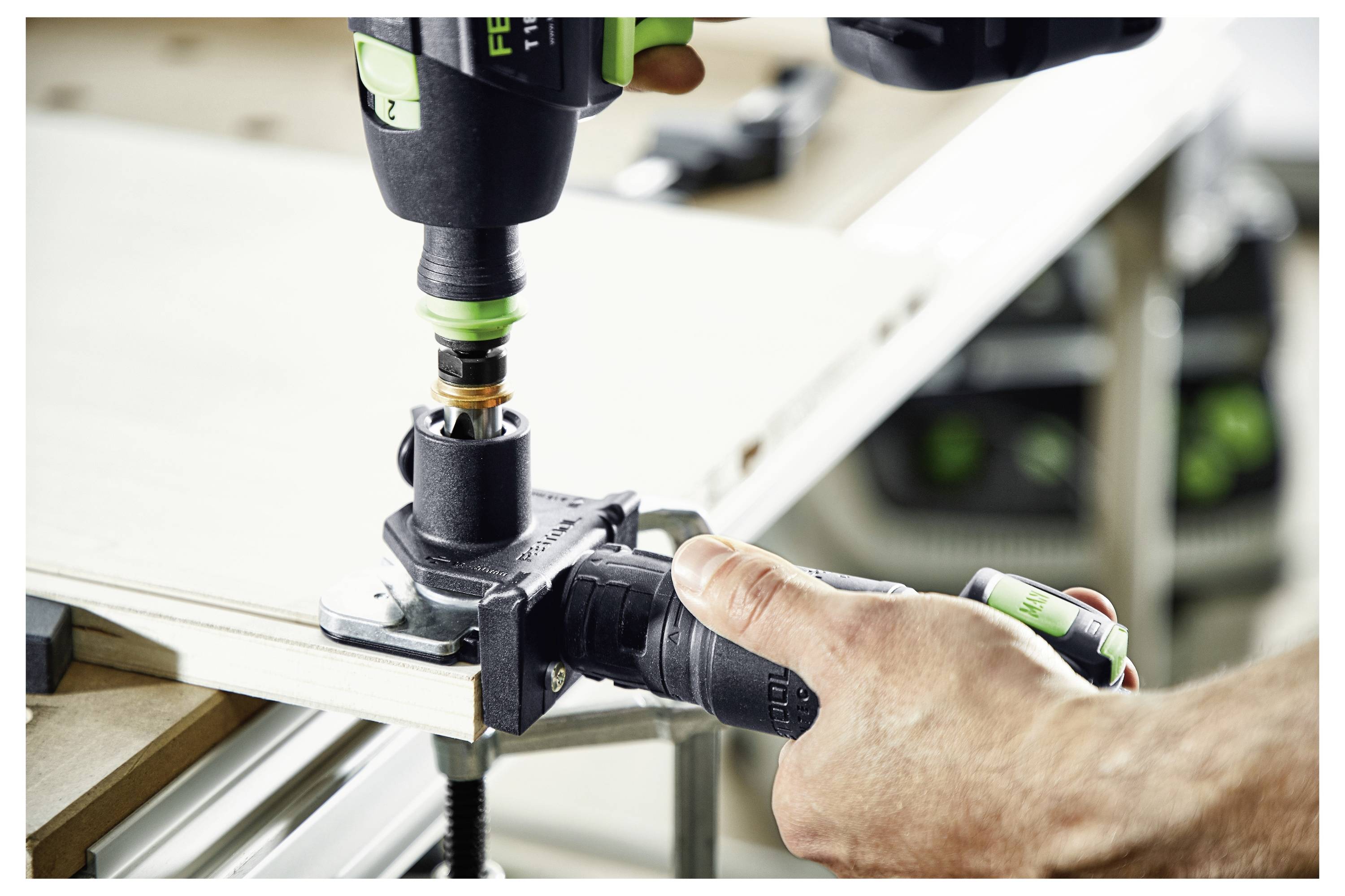 Eine Person verwendet einen Bohrer mit einer kreisförmigen Aufsatz auf einem Holzstück, das durch eine Klemme gesichert ist. Der Fokus liegt auf dem Holzbearbeitungsprozess.