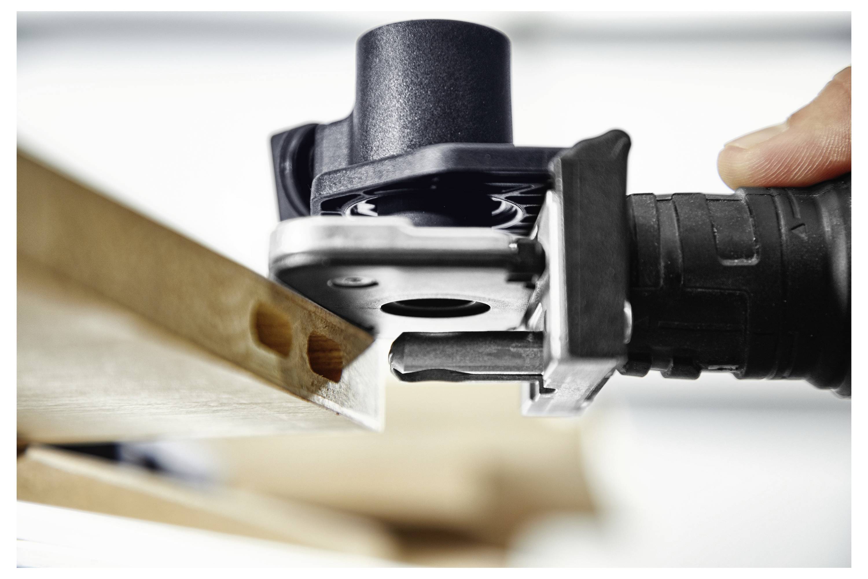 Eine Person benutzt ein schwarz-grünes Elektrowerkzeug, um Schrauben in eine Wand einzudrehen, wobei eine Reihe von Schrauben für die automatische Zuführung aufgereiht ist.