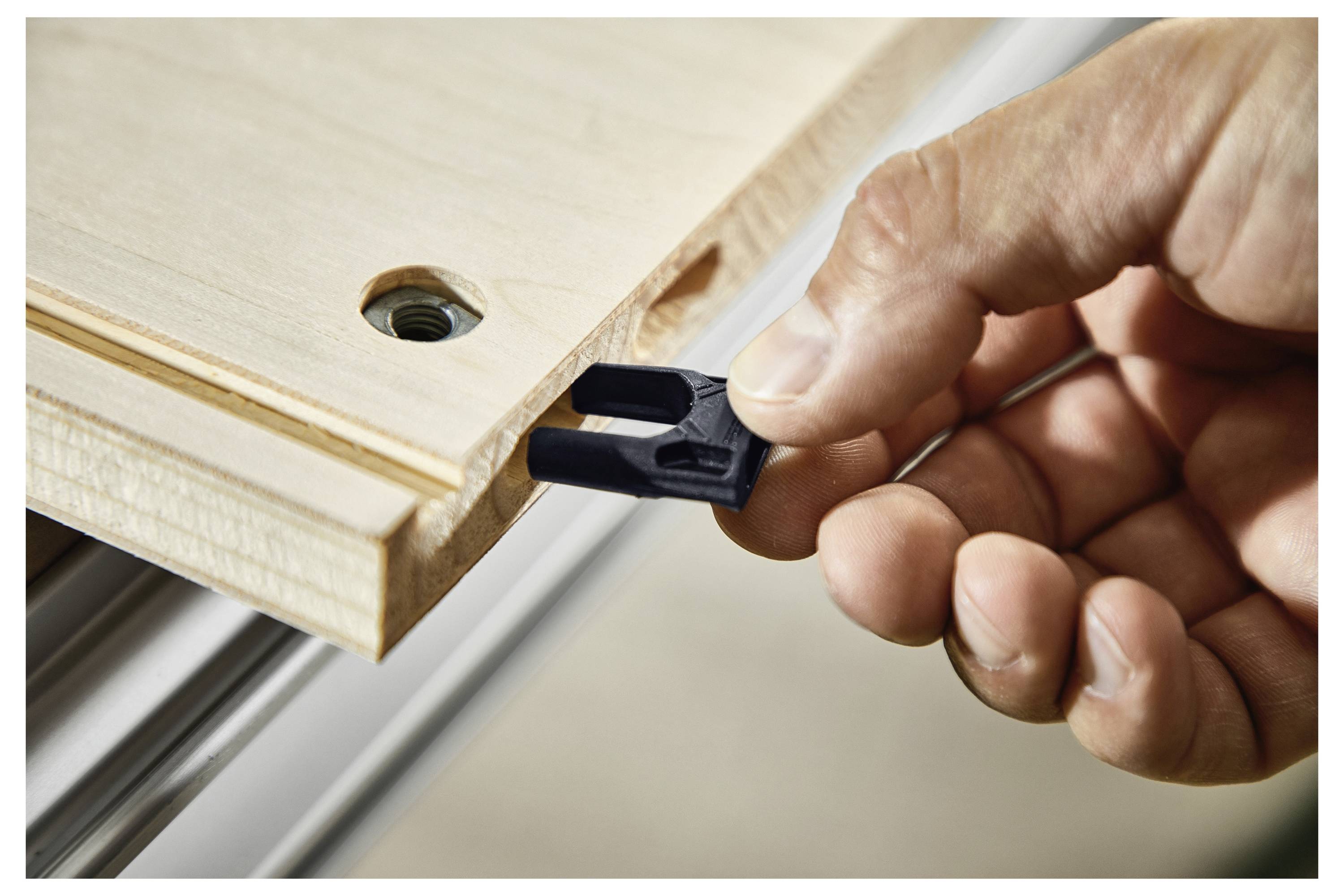 Eine Person benutzt einen Wandschleiffer in einem unvollendeten Raum. Ein am Schleiffer angebrachter Staubsauger sammelt Staub. Wände sind mit Trockenbauteilen bedeckt.