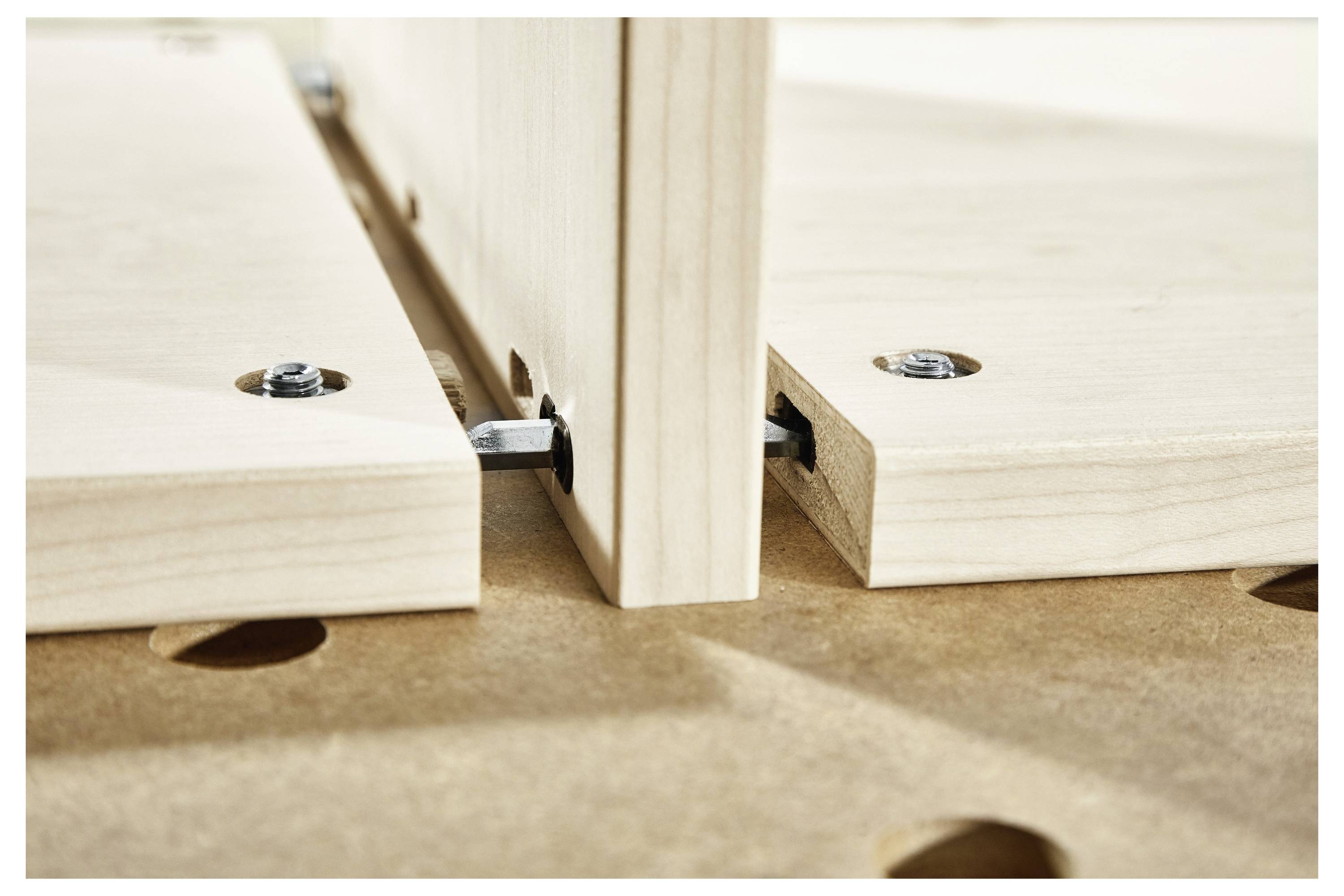 Nahaufnahme von Holzbrettern, die mit Verbindungselementen zusammengefügt werden, wobei das DIY-Möbelzusammenbau oder das Holzbearbeitungsdetail hervorgehoben wird.