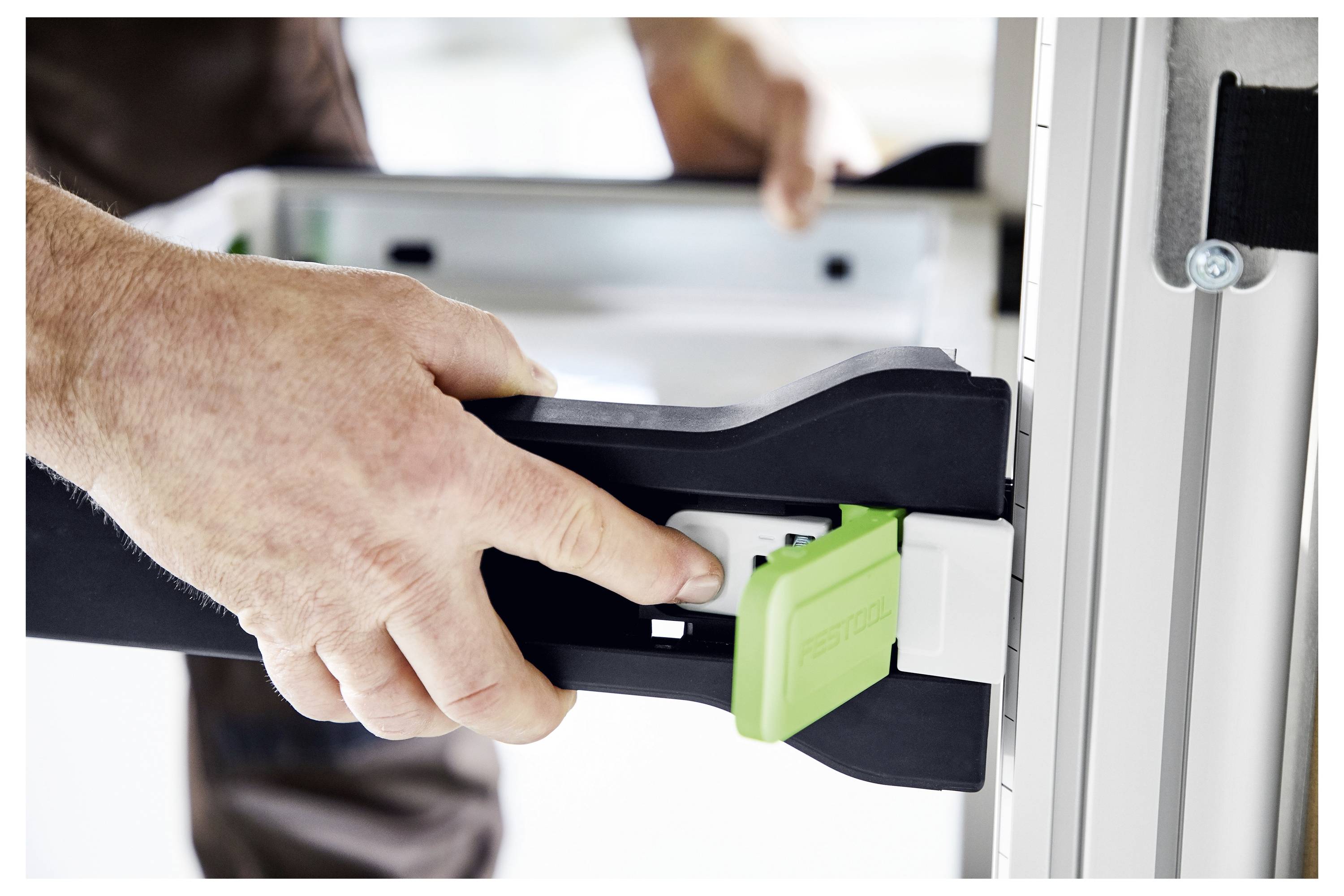 Nahaufnahme einer Hand einer Person, die eine Klemme an einem Metallrahmen einstellt, was präzise Handhabung von Werkzeugen für Bau- oder Montagearbeiten demonstriert.