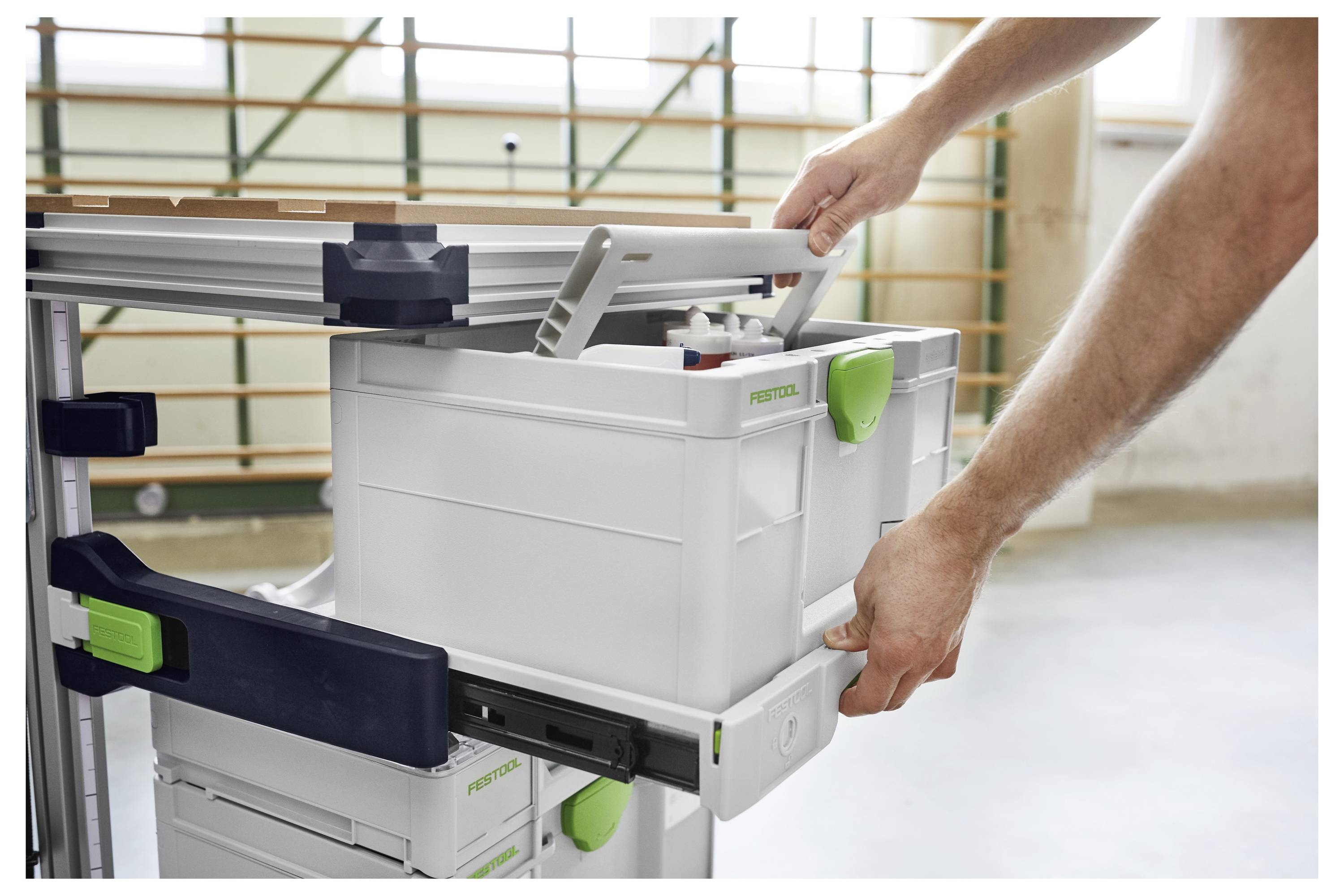 Festool OF 1010 EQ Oberfräse auf einer Werkbank, die präzise Schwalbenschwanzverbindungen in Holzteile schneidet, umgeben von Holzbearbeitungswerkzeugen.