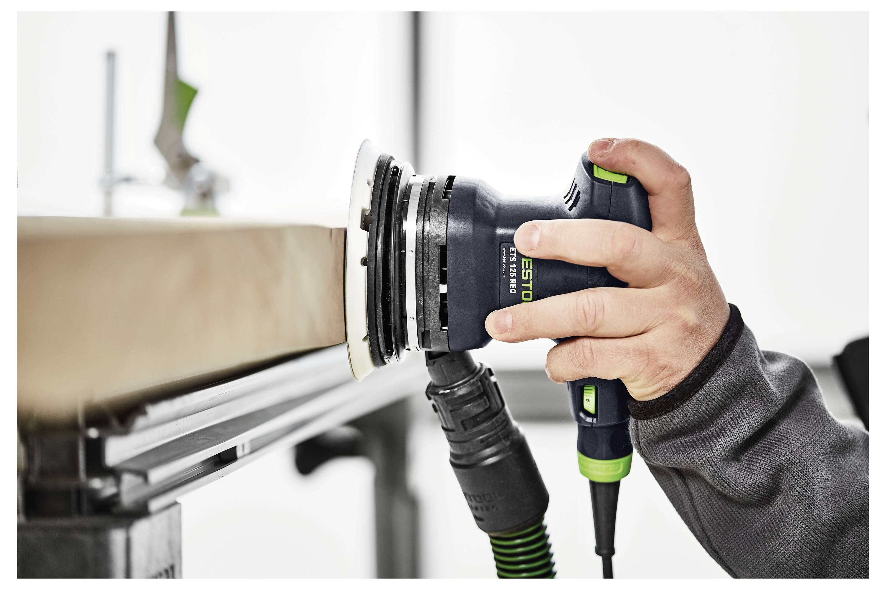 Eine Person verwendet einen elektrischen Schleiffer, um eine Holzoberfläche zu glätten, wobei eine Nahaufnahme des Werkzeugs in Aktion gezeigt wird, mit Fokus auf Präzision.