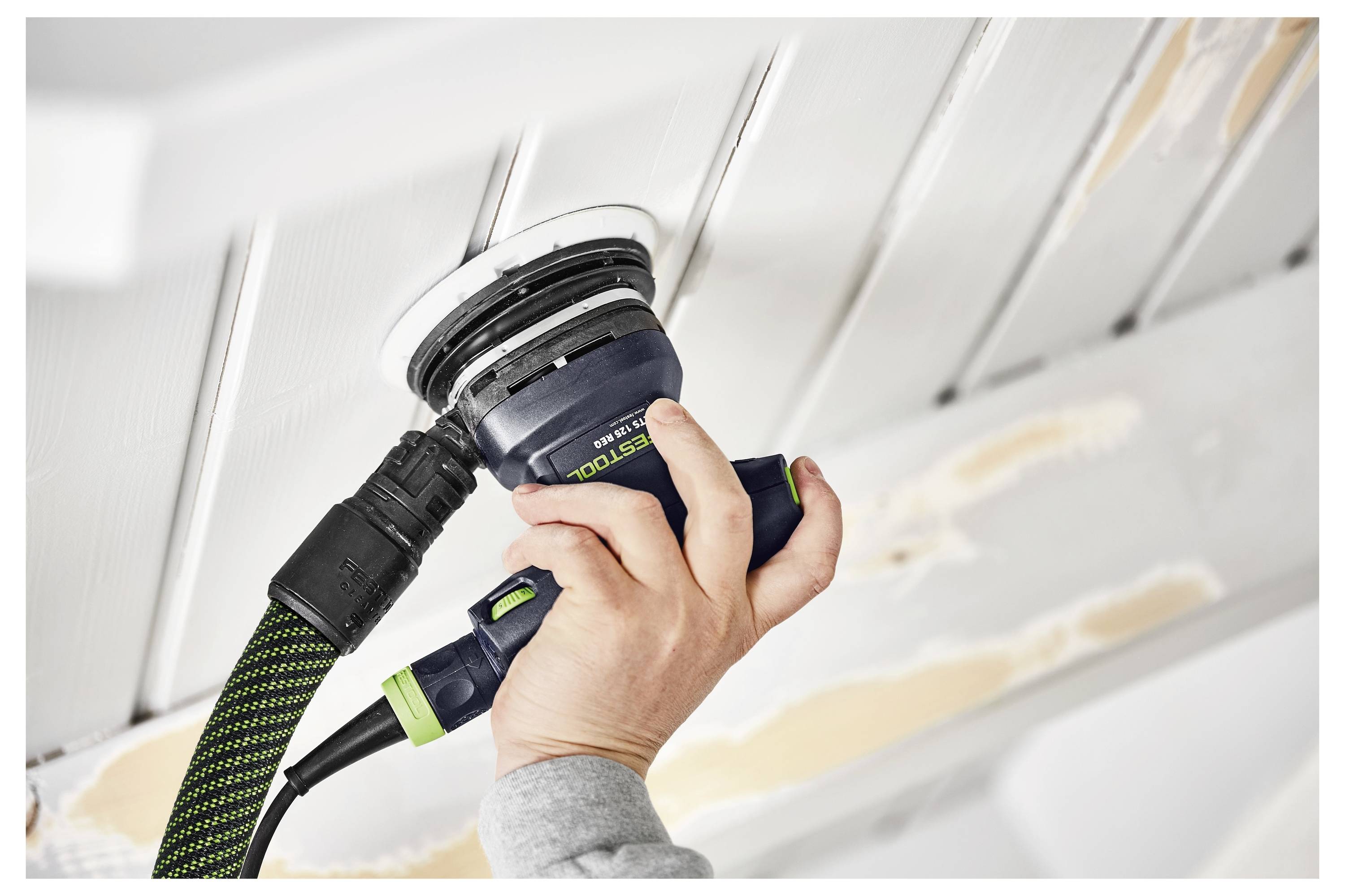 Eine Person verwendet einen tragbaren Elektroschleifen an einer Decke und glättet die Oberfläche.