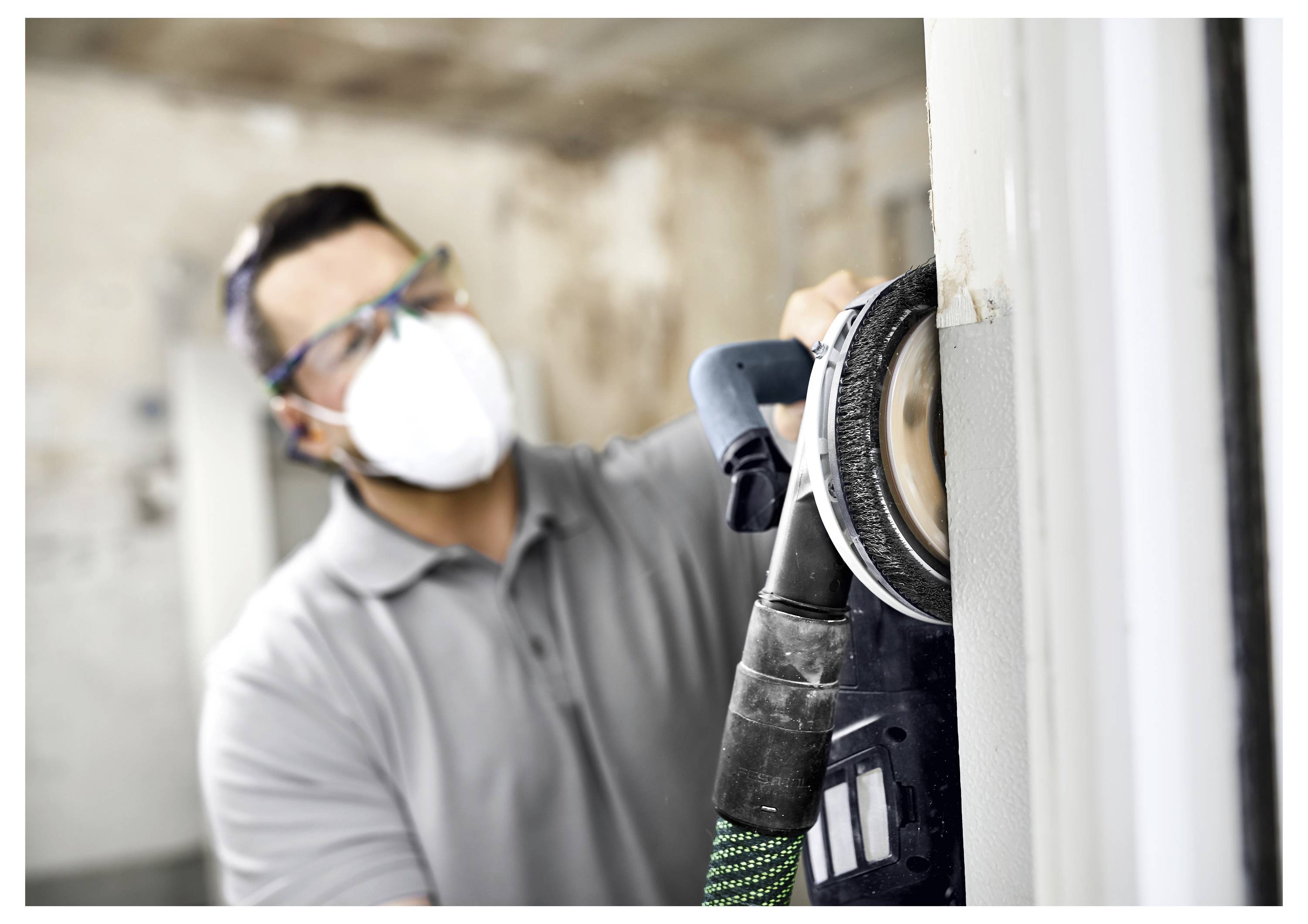 Eine Person bedient einen schwarzen und grünen Festool-Trockenbau-Schraubendreher und befestigt schnell Schrauben in einer weißen Wand mit einem automatischen Zuführungssystem.