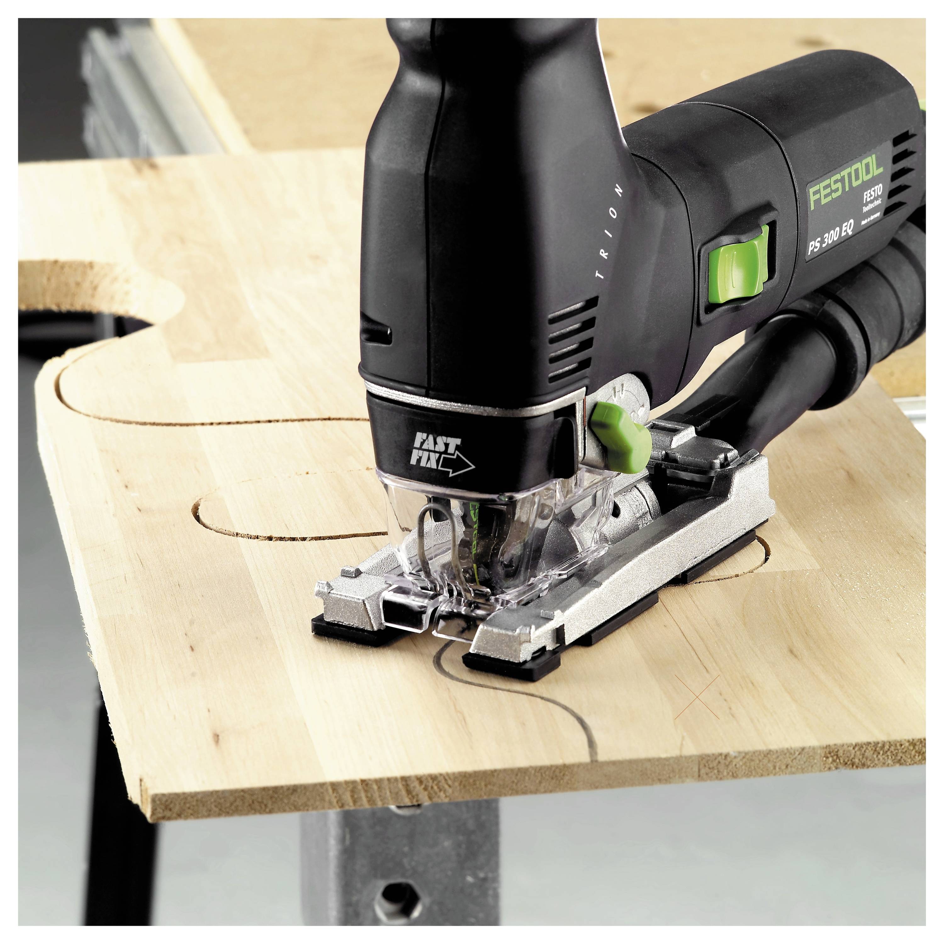 Eine Festool-Stichsäge schneidet ein geschwungenes Muster in ein Stück Holz auf einer Werkstatt, wobei präzise Holzbearbeitungswerkzeuge und Techniken demonstriert werden.