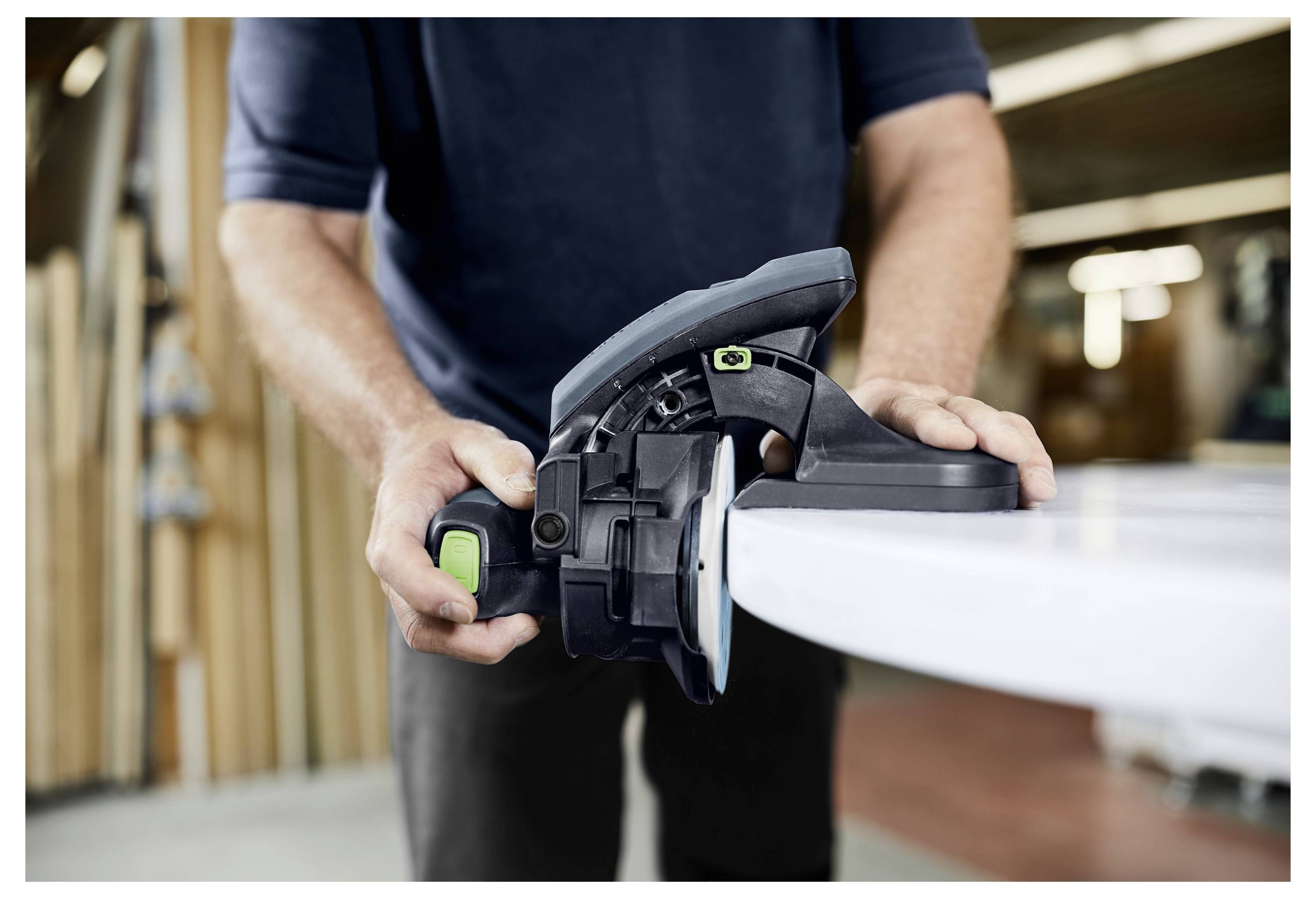 Eine Person nutzt eine Kreissäge, um ein Holzbrett in einer Werkstatt zu schneiden, mit Fokus auf das Werkzeug und die Handlung.