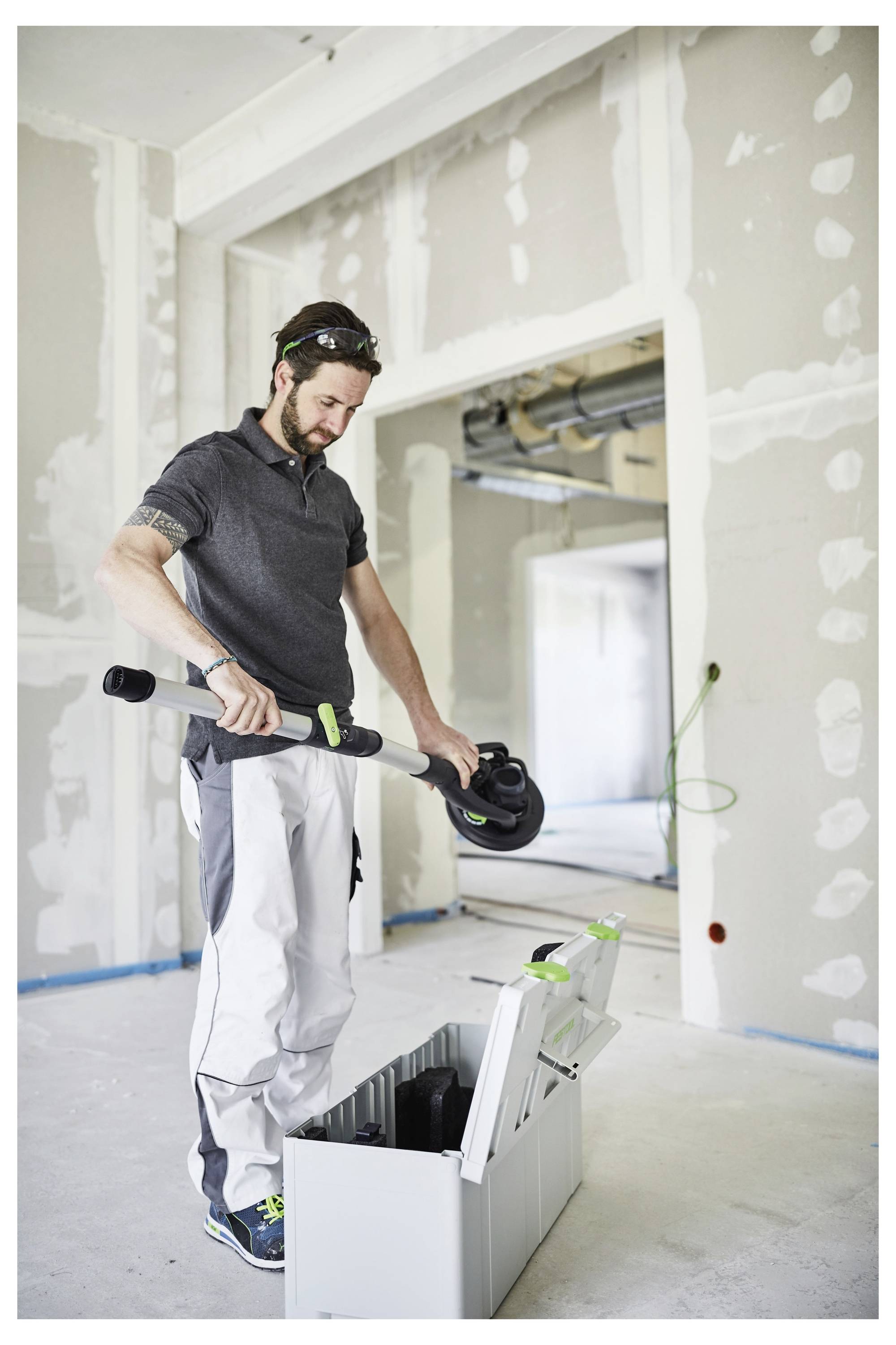 Eine Person, die drinnen ein Werkzeug zusammenbaut oder auseinandernimmt, wahrscheinlich für Bau- oder Renovierungsarbeiten, mit hellfarbigen Wänden im Hintergrund.