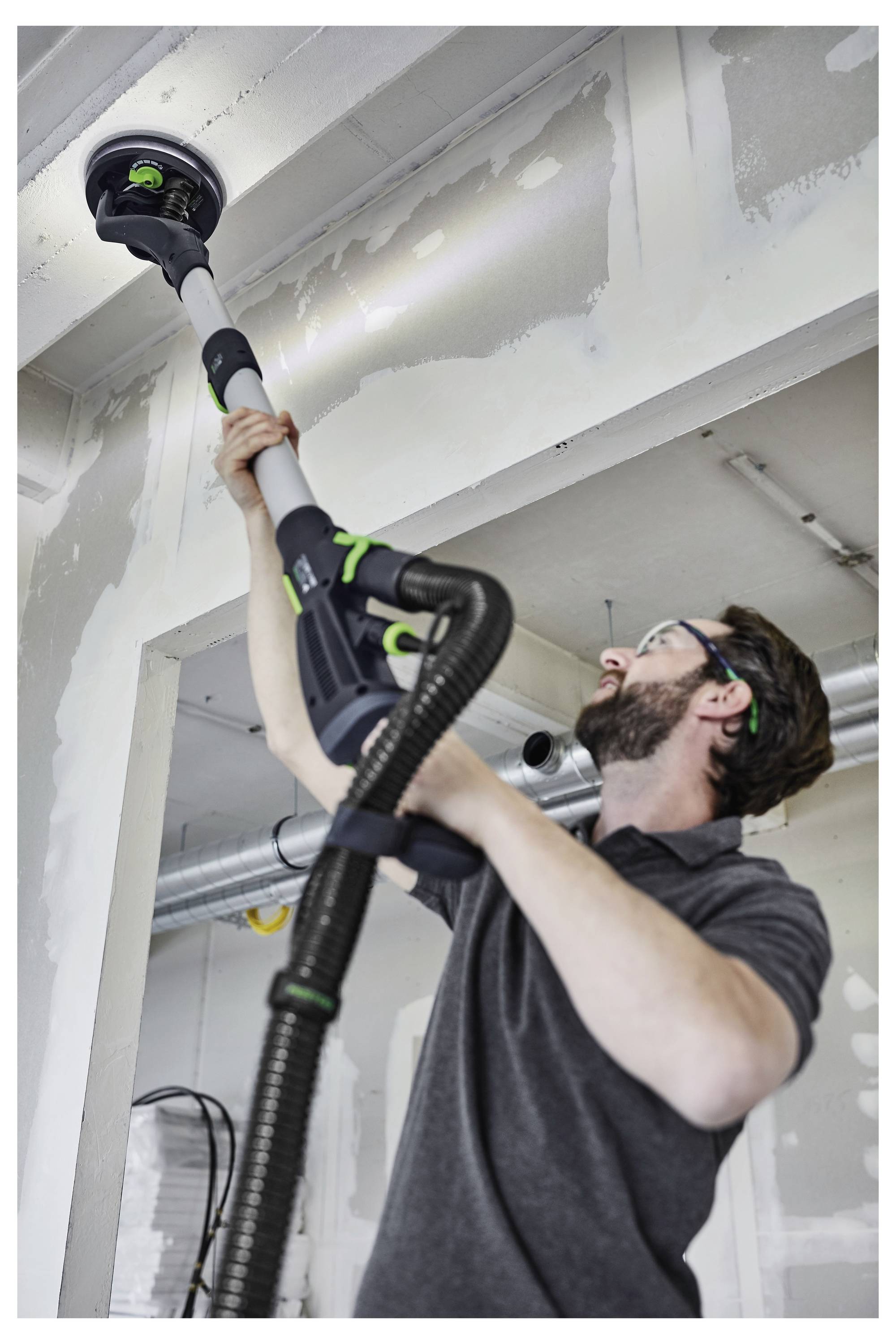 Eine Hand stellt eine Maschinenkomponente in einer Werkstatt ein, wobei der Fokus auf dem Hebel und den Metallteilen liegt.