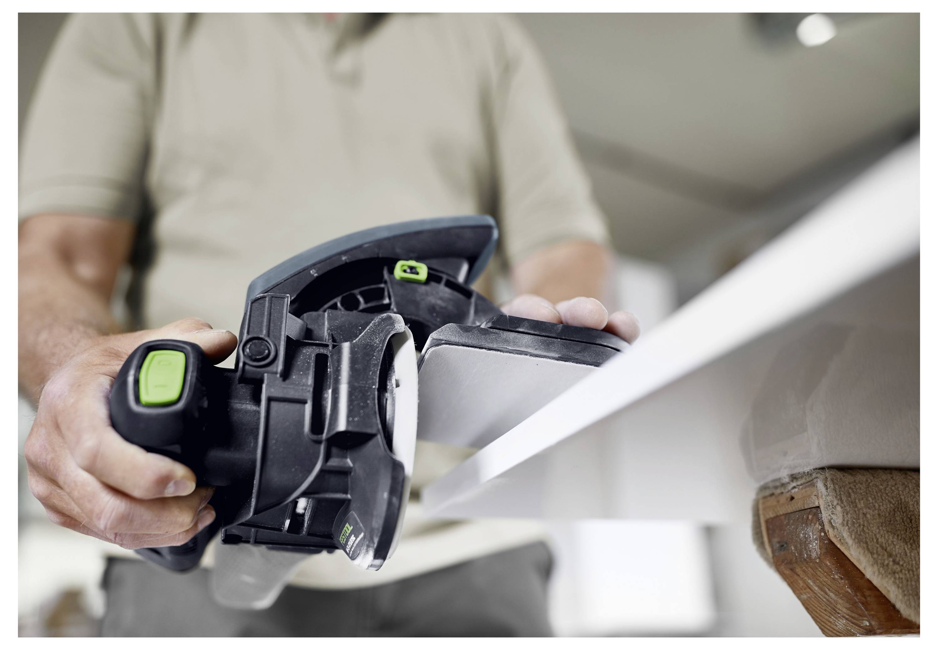 Eine Person benutzt einen Elektro-Hobel auf einer Holzoberfläche und glättet die Kanten. Das Werkzeug wird fest gehalten, und Holzspäne sind sichtbar.